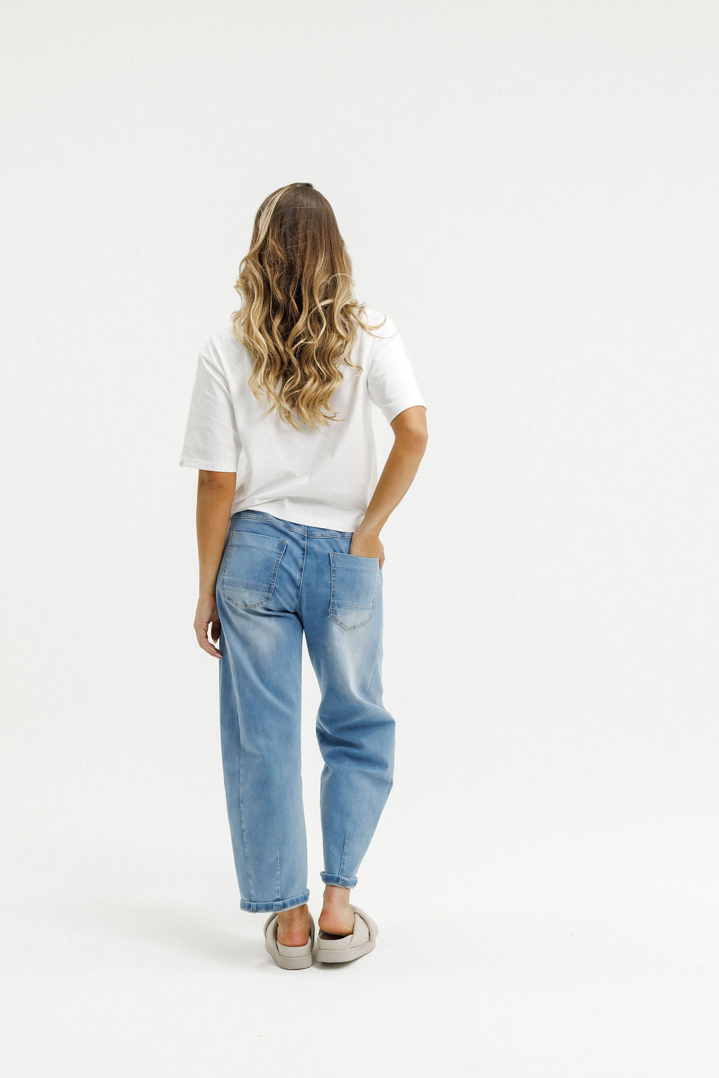 Person wearing a white t-shirt and light blue jeans on a white background