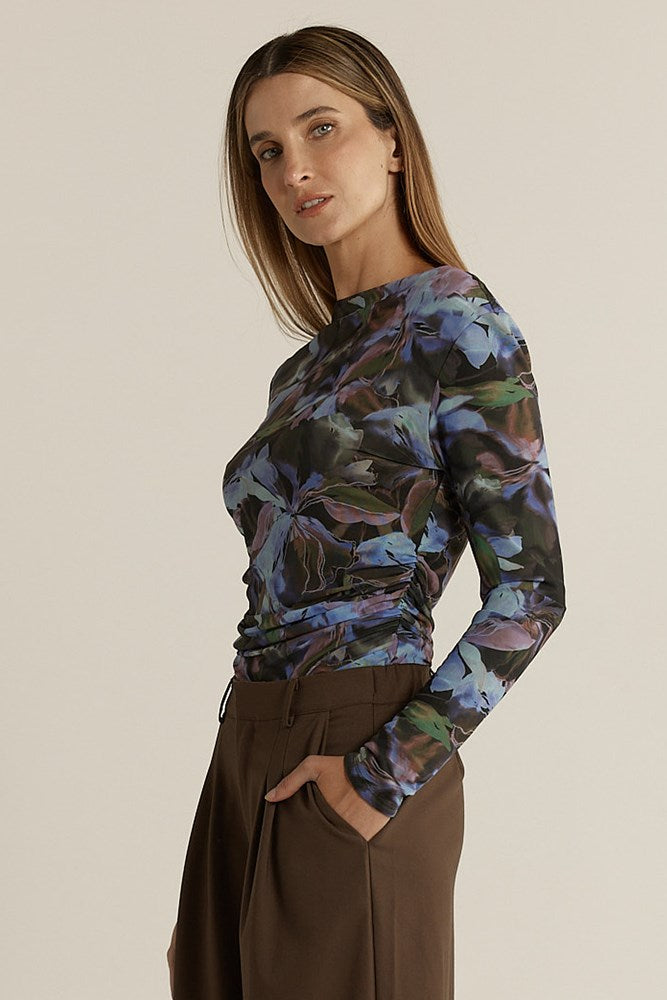 Woman wearing a long-sleeve floral top and brown pants on a beige background