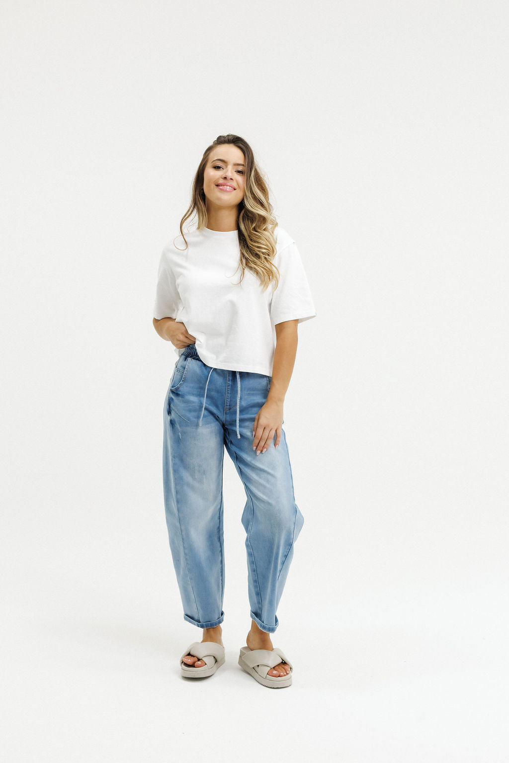 Woman wearing a white t-shirt and blue jeans on a white background