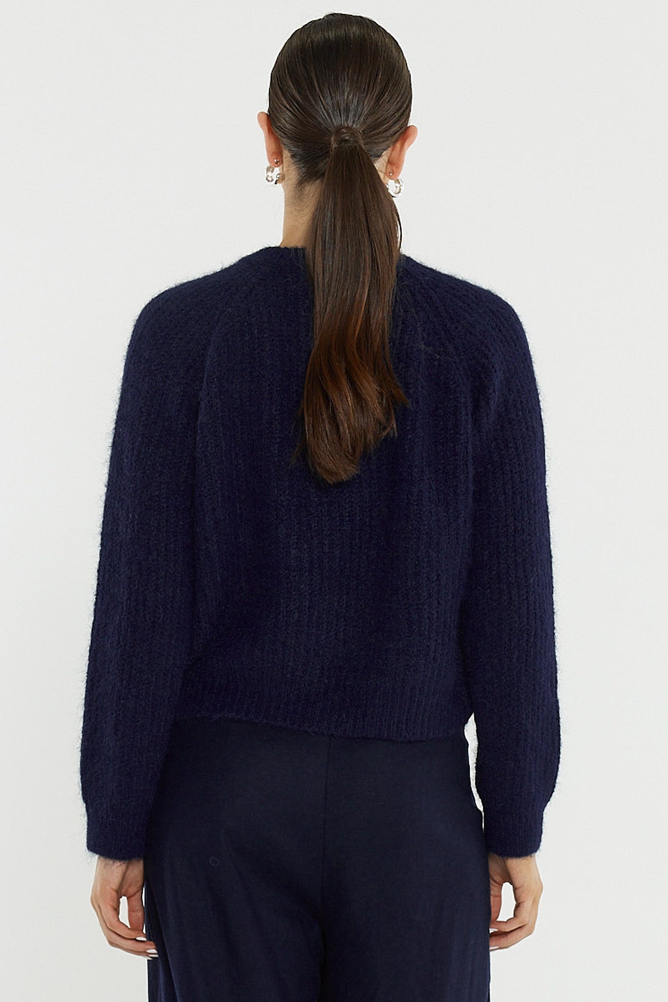 Person wearing a dark blue sweater against a white background