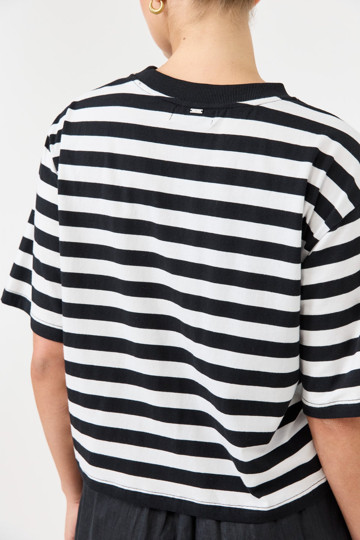 Person wearing a black and white striped shirt on a plain background