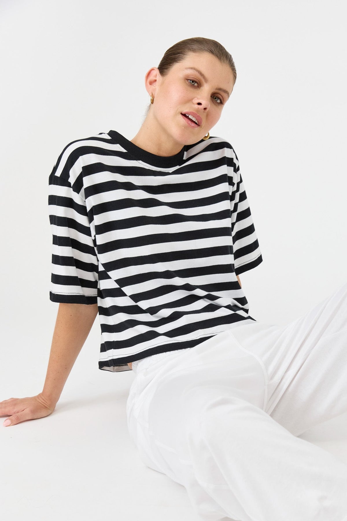 Person wearing a black and white striped sweater sitting on a white surface.