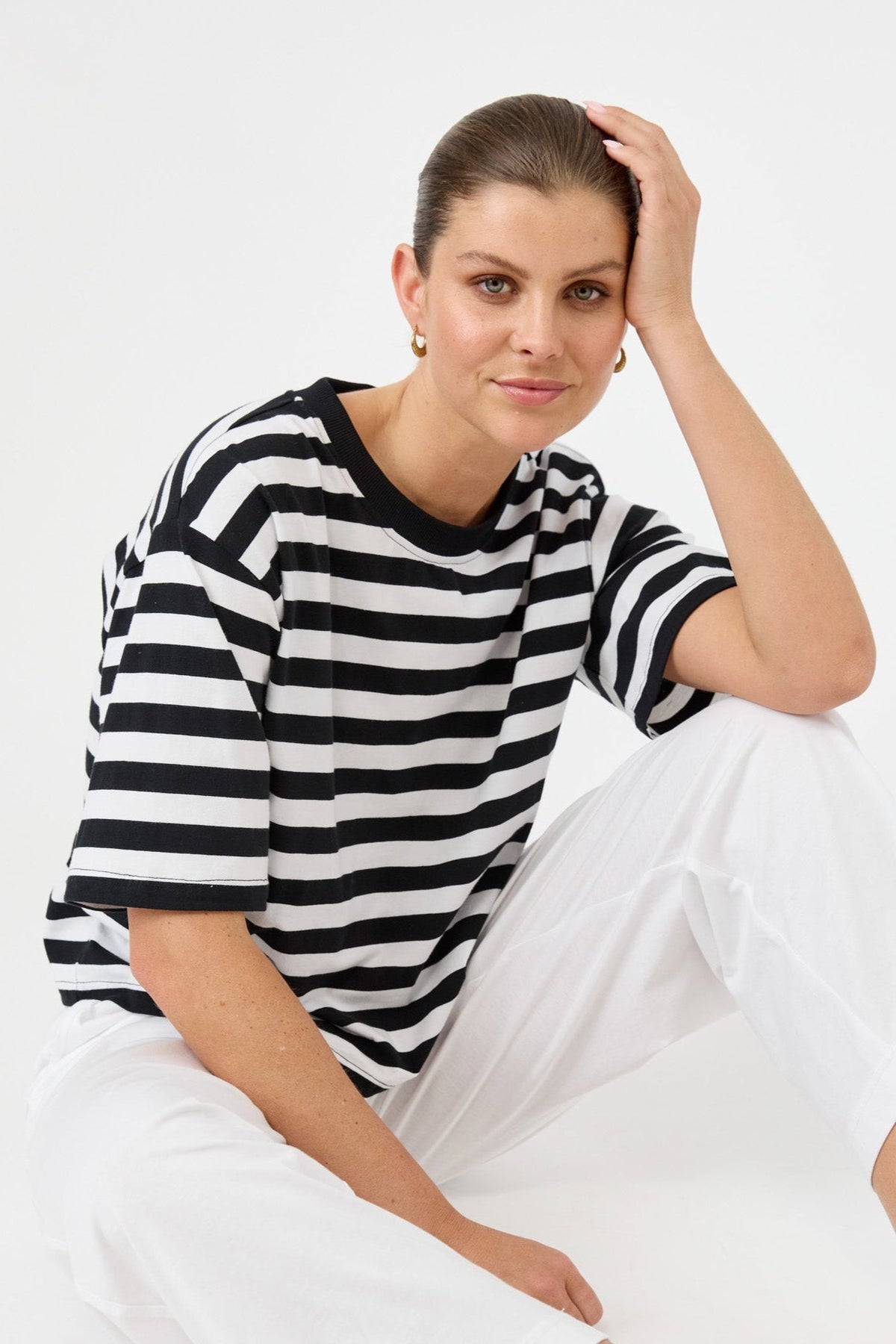 Woman wearing a black and white striped shirt sitting on a white background