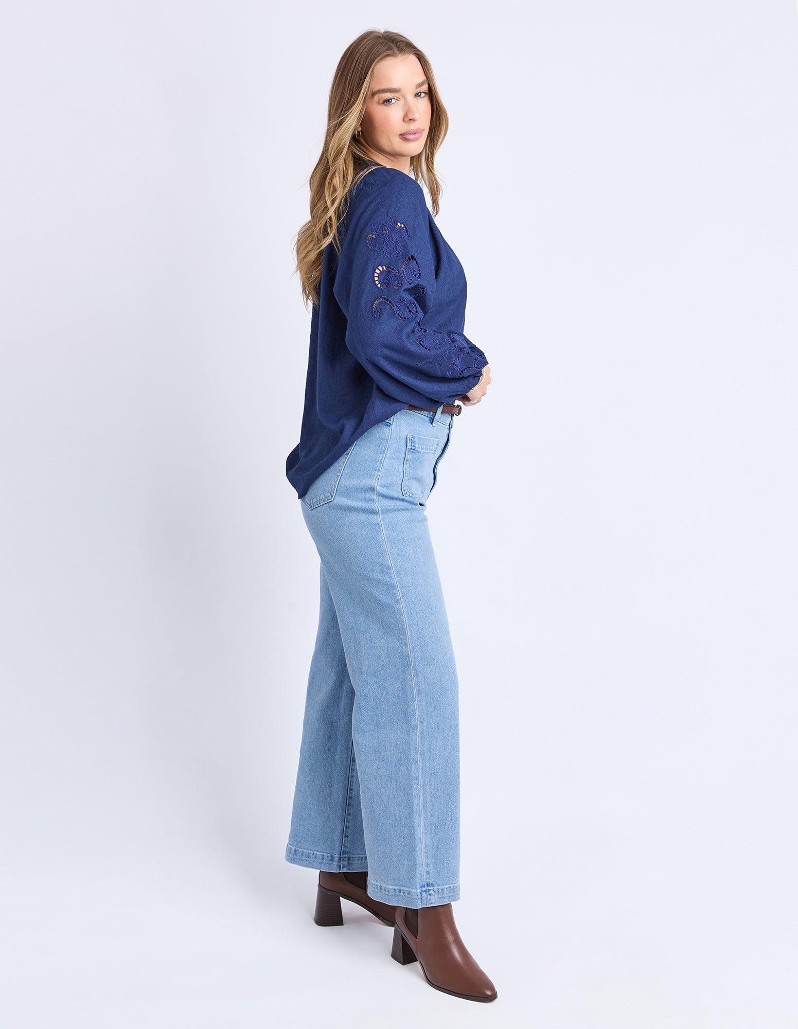 Woman wearing a blue sweater and light blue jeans on a white background
