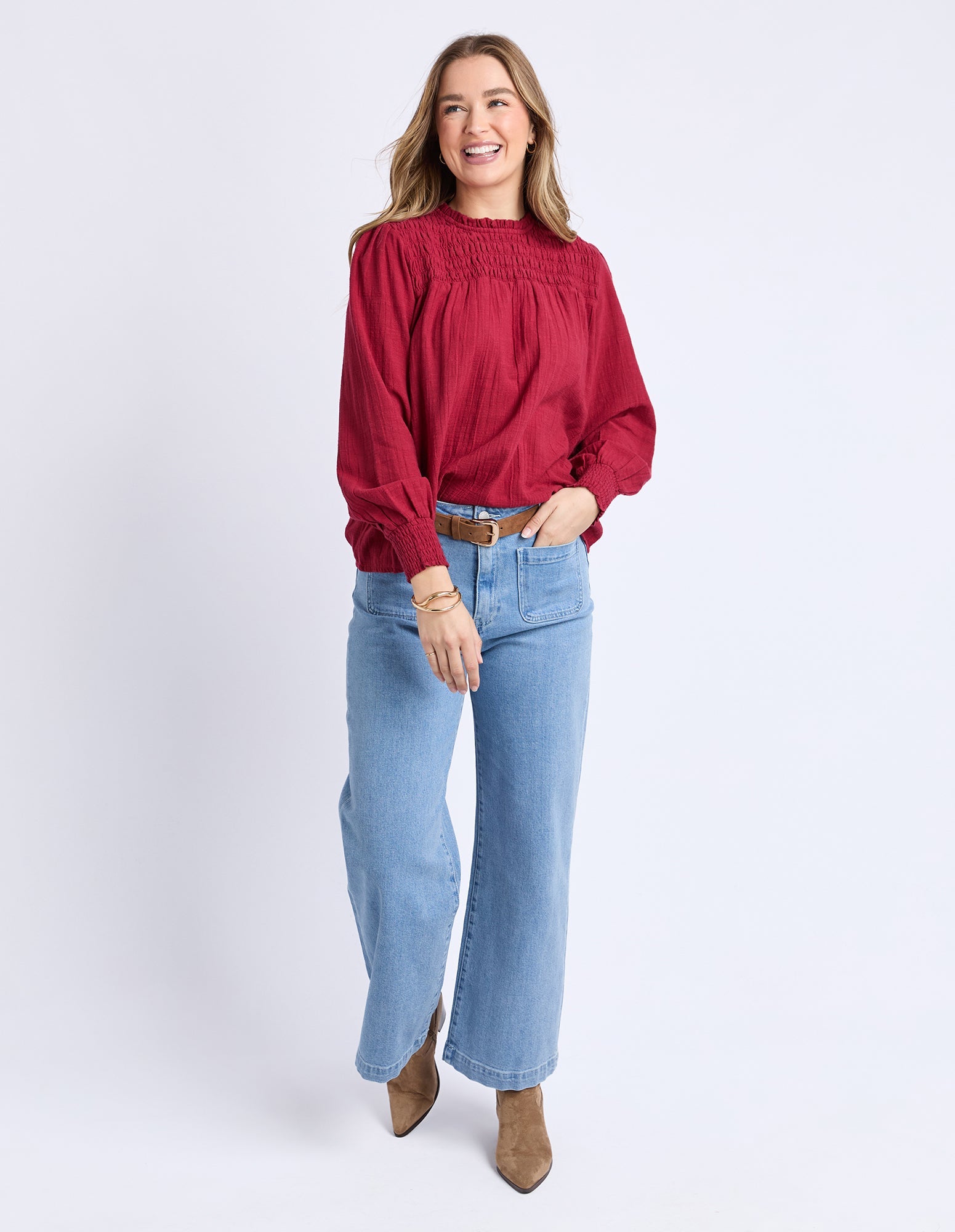 Woman wearing a red blouse and light blue jeans on a white background