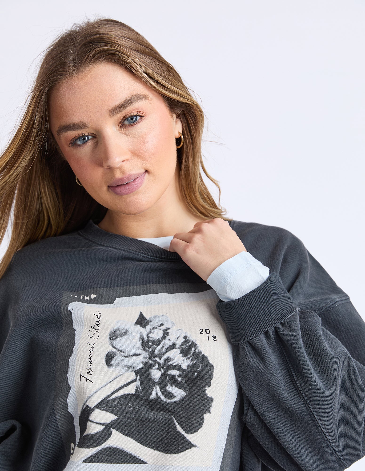 Woman wearing a dark gray sweatshirt with a floral design on a white background