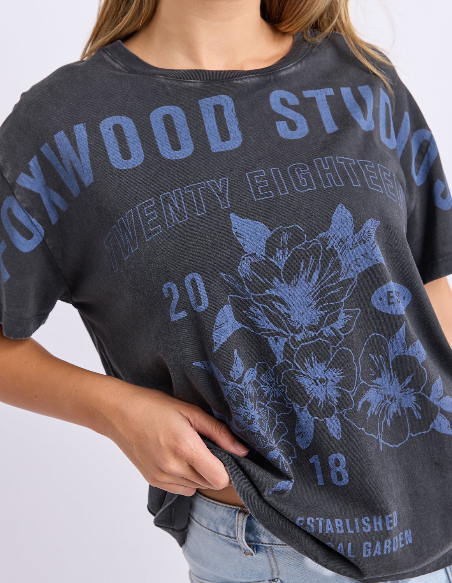 Person wearing a dark gray t-shirt with blue graphics and text on a white background