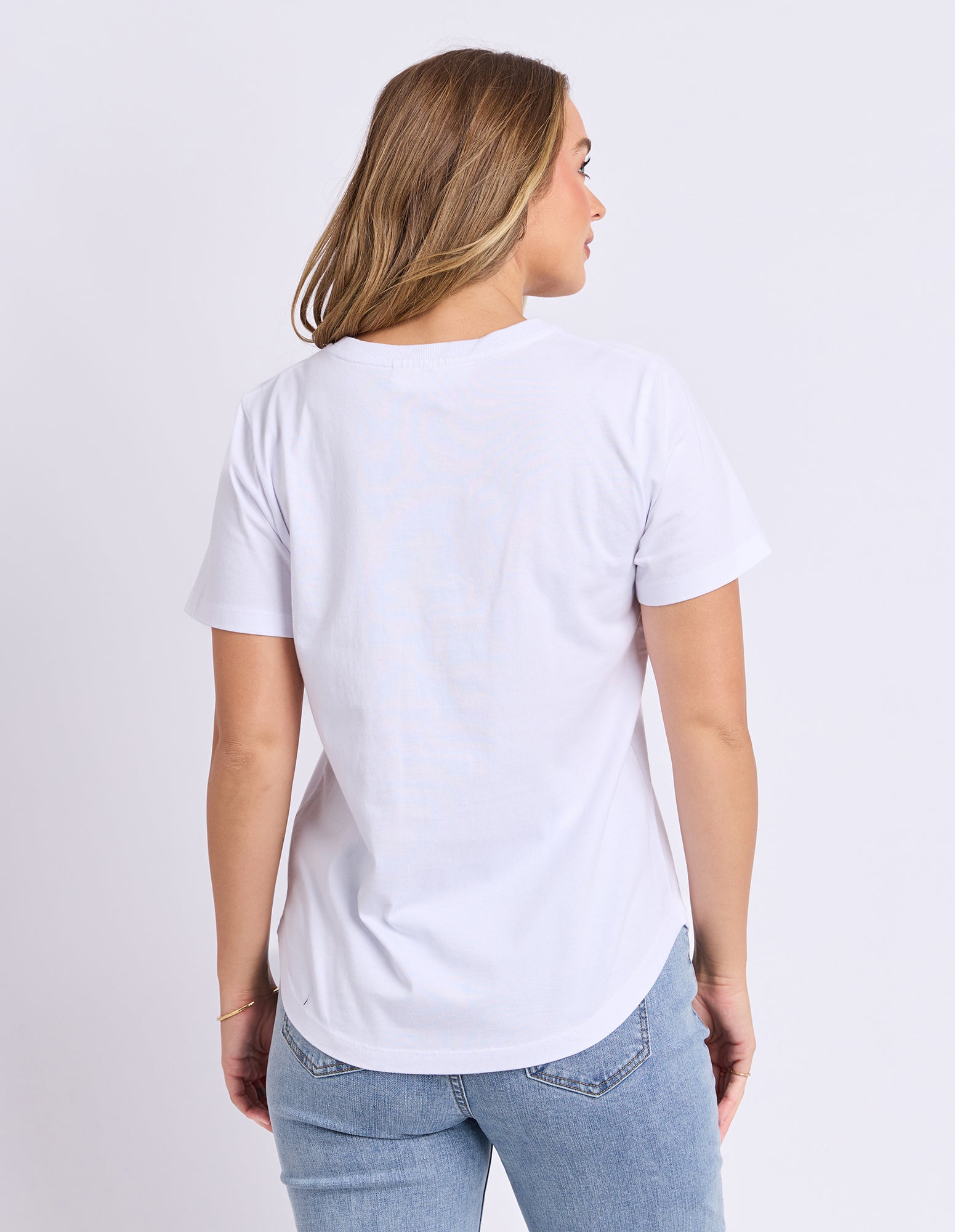 Woman wearing a plain white t-shirt and light blue jeans on a light gray background