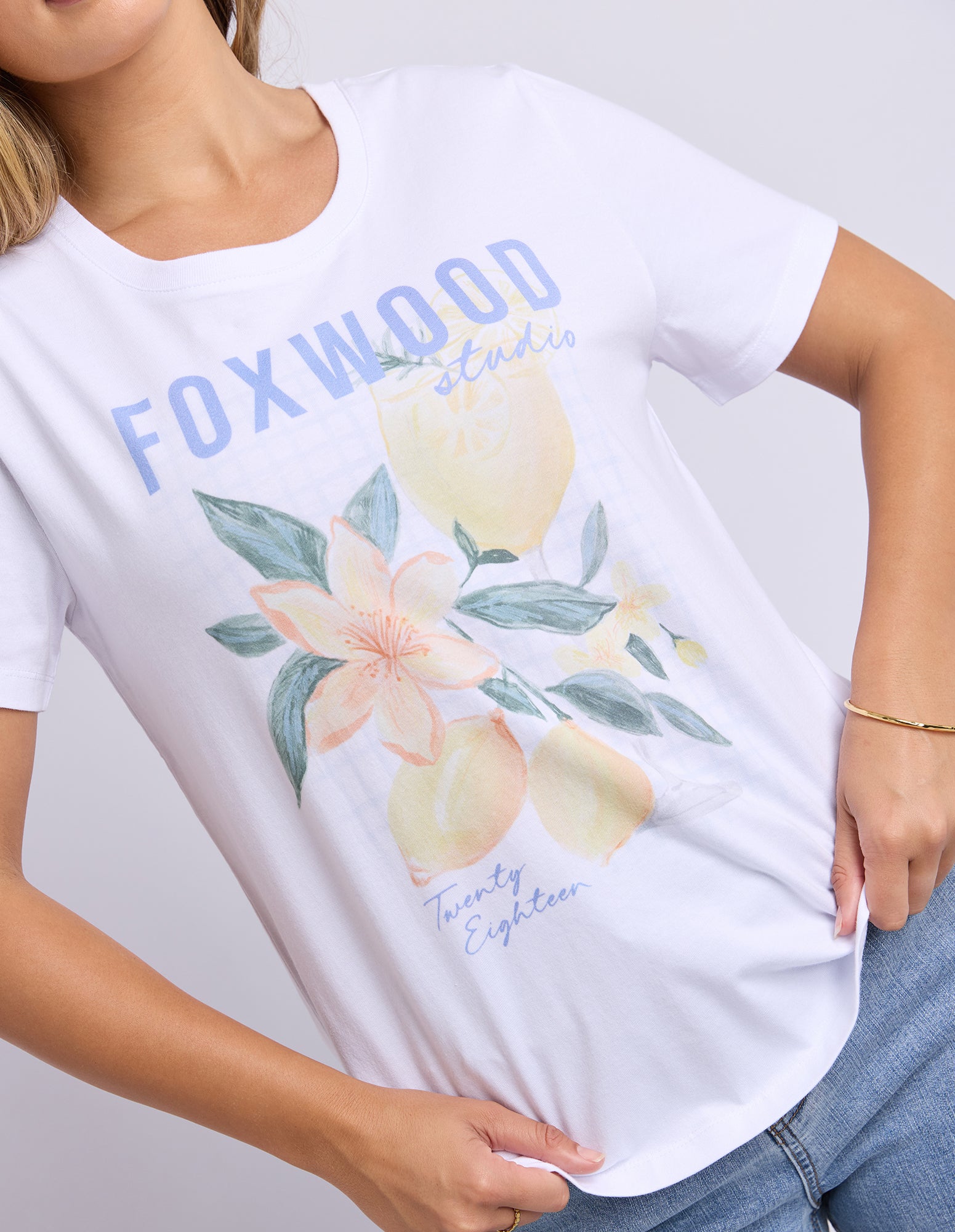 White t-shirt with floral design and 'FOXWOOD' branding on a plain background