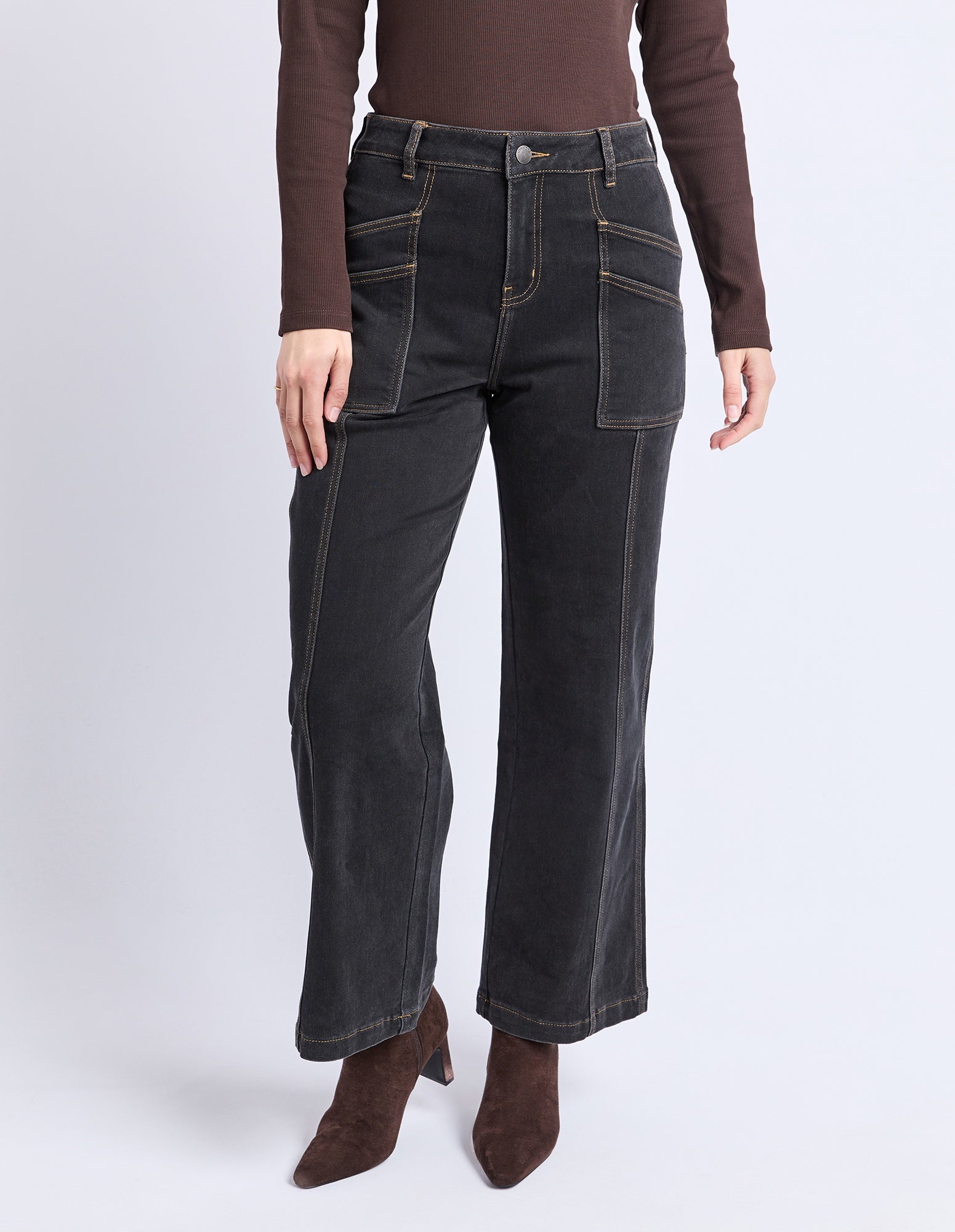 Person wearing dark jeans and brown top on a white background