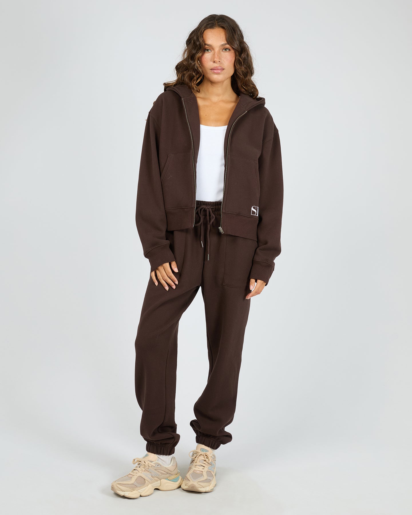 Woman wearing a brown tracksuit with a white background