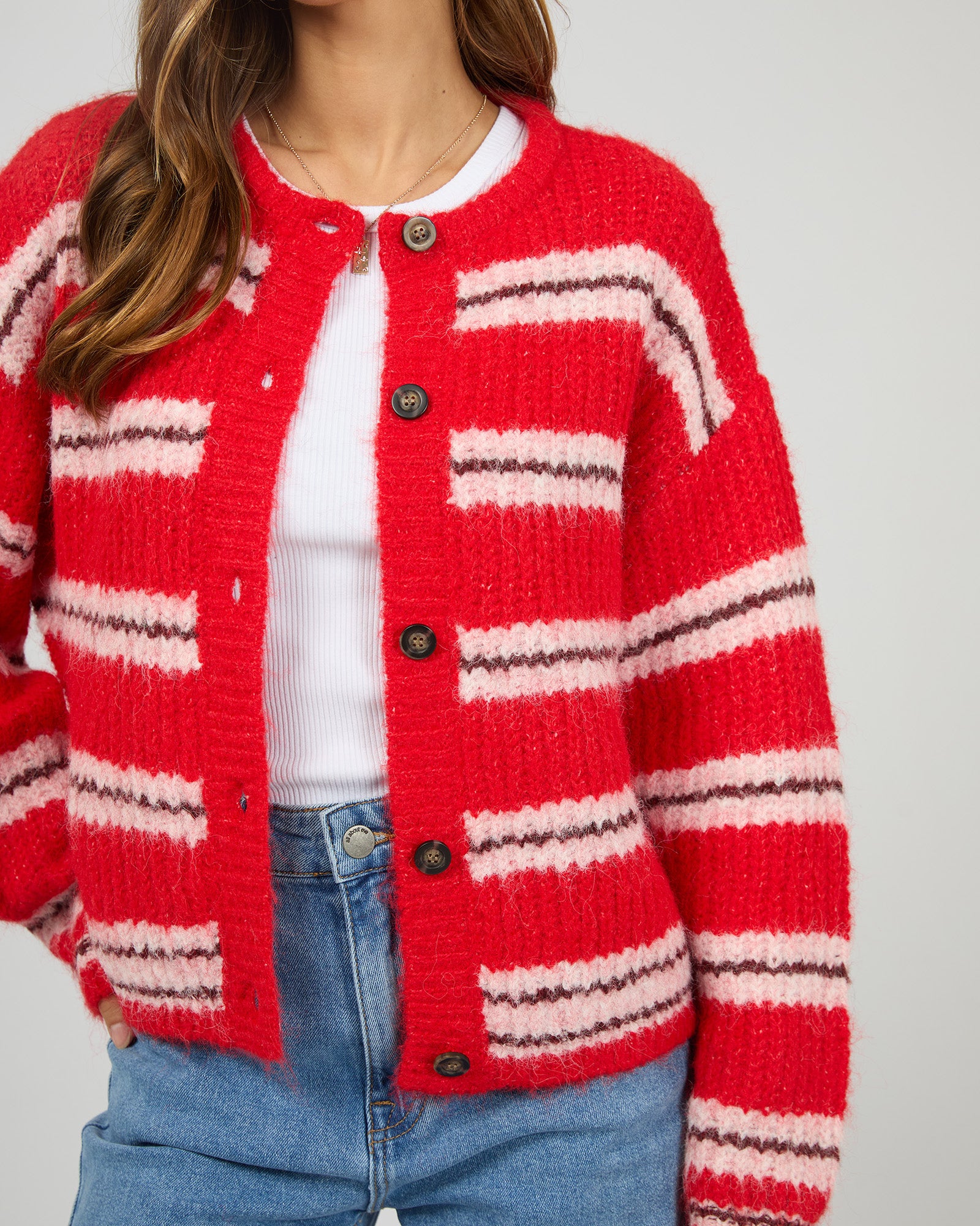 Red and white striped cardigan worn by a person on a plain background