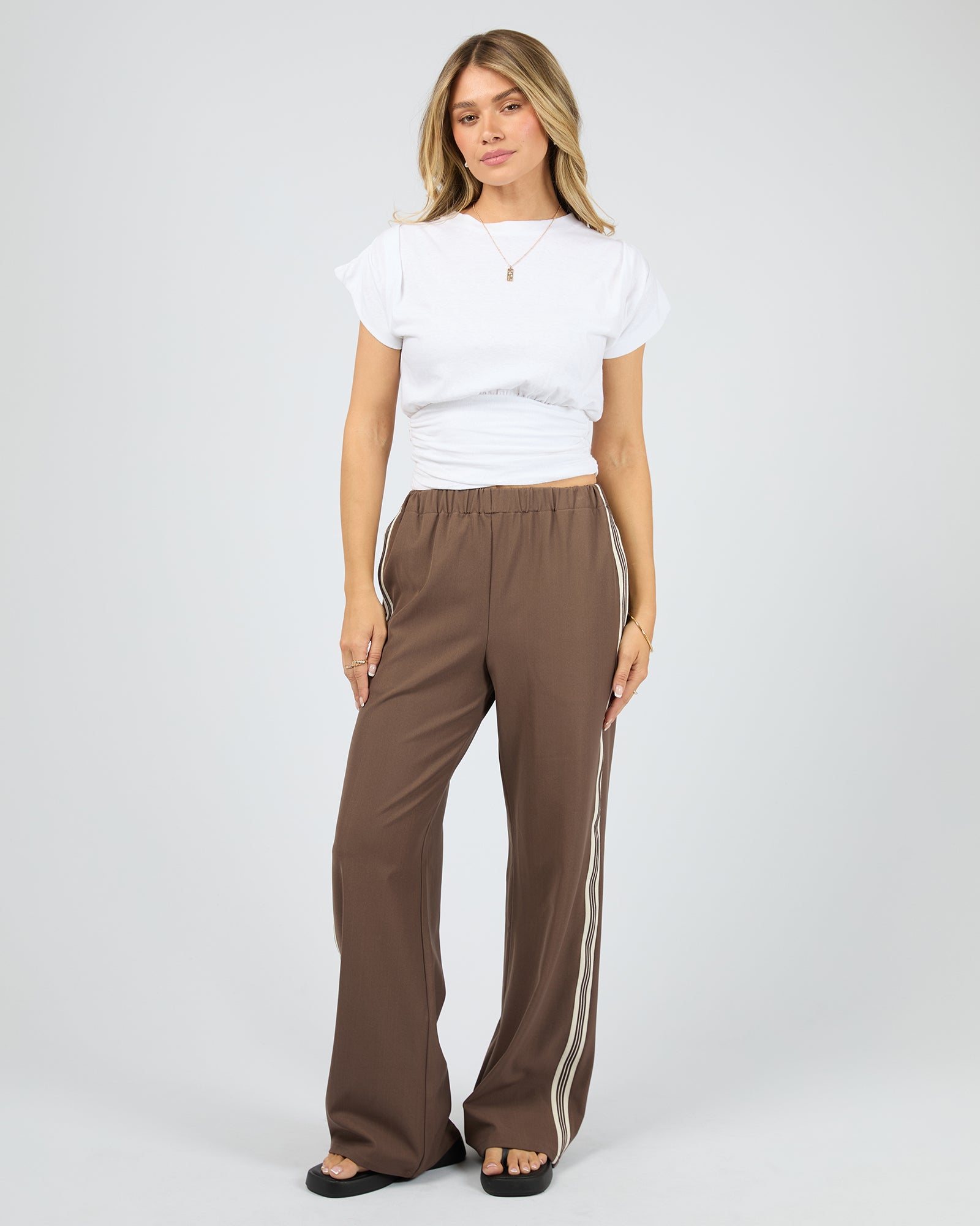 Woman wearing brown pants with white stripes on a white background