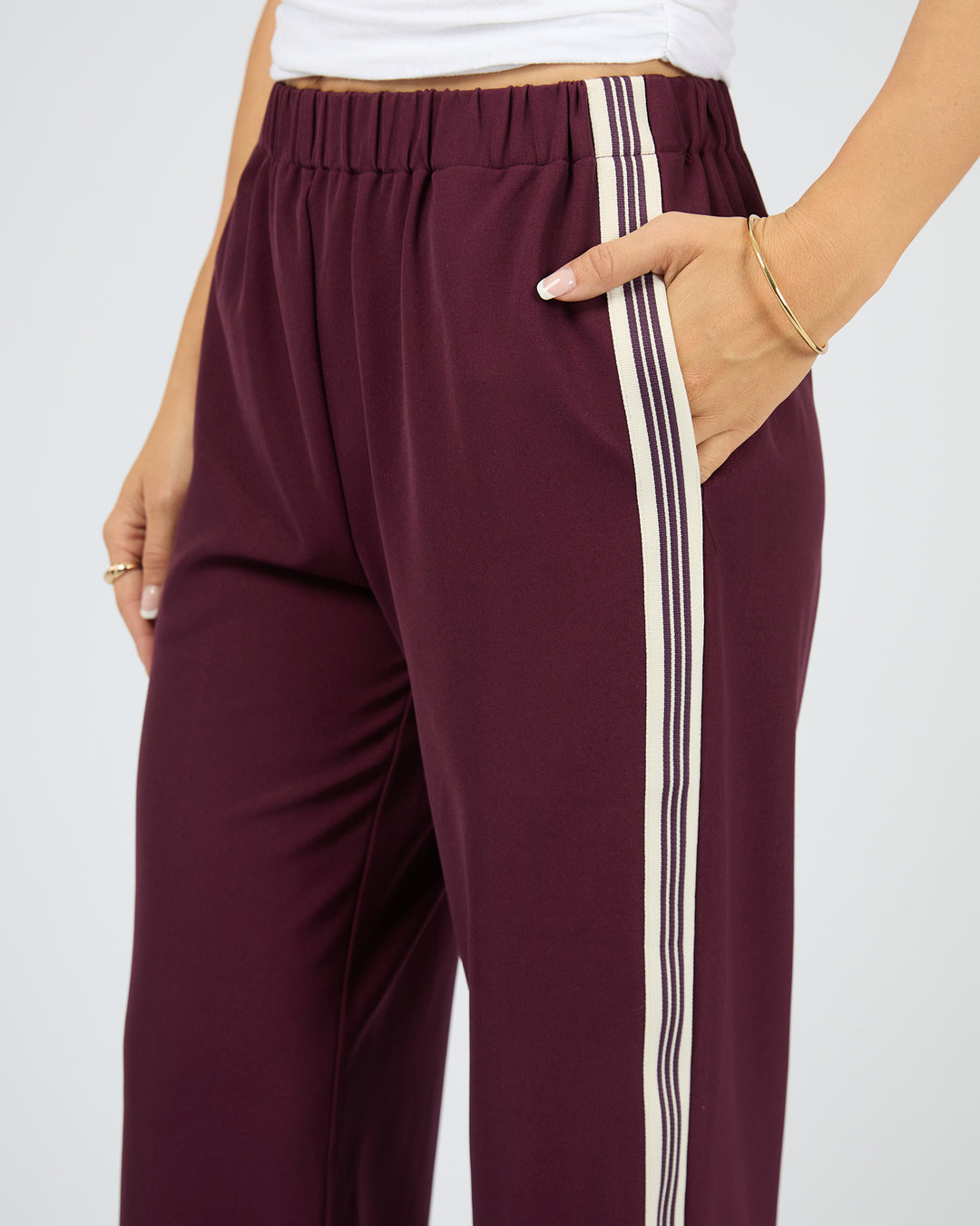 Maroon pants with white stripes on a plain background
