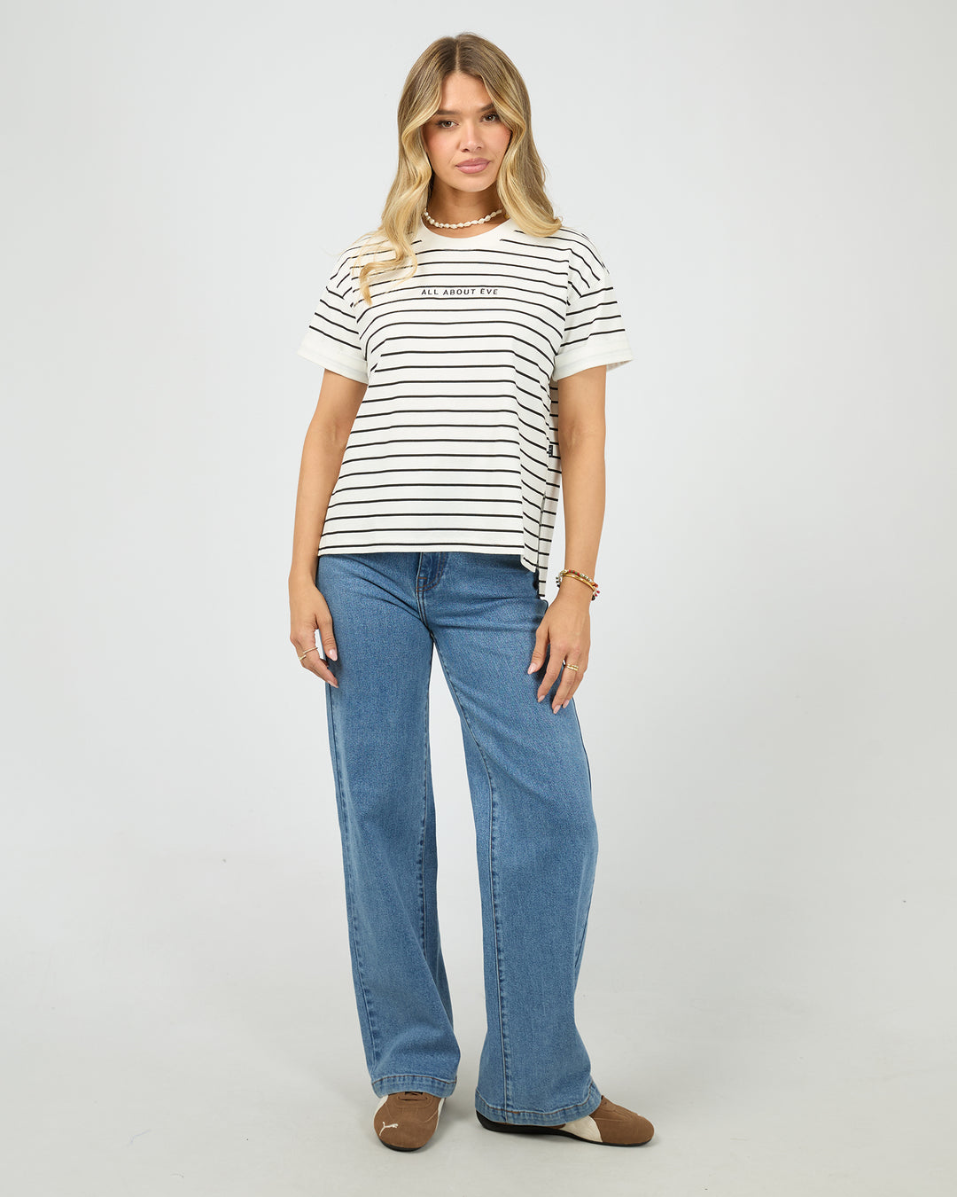 Woman wearing a striped shirt and blue jeans on a white background