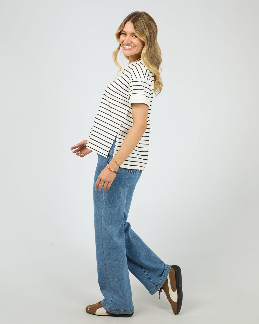 Woman wearing a striped shirt and blue jeans on a white background