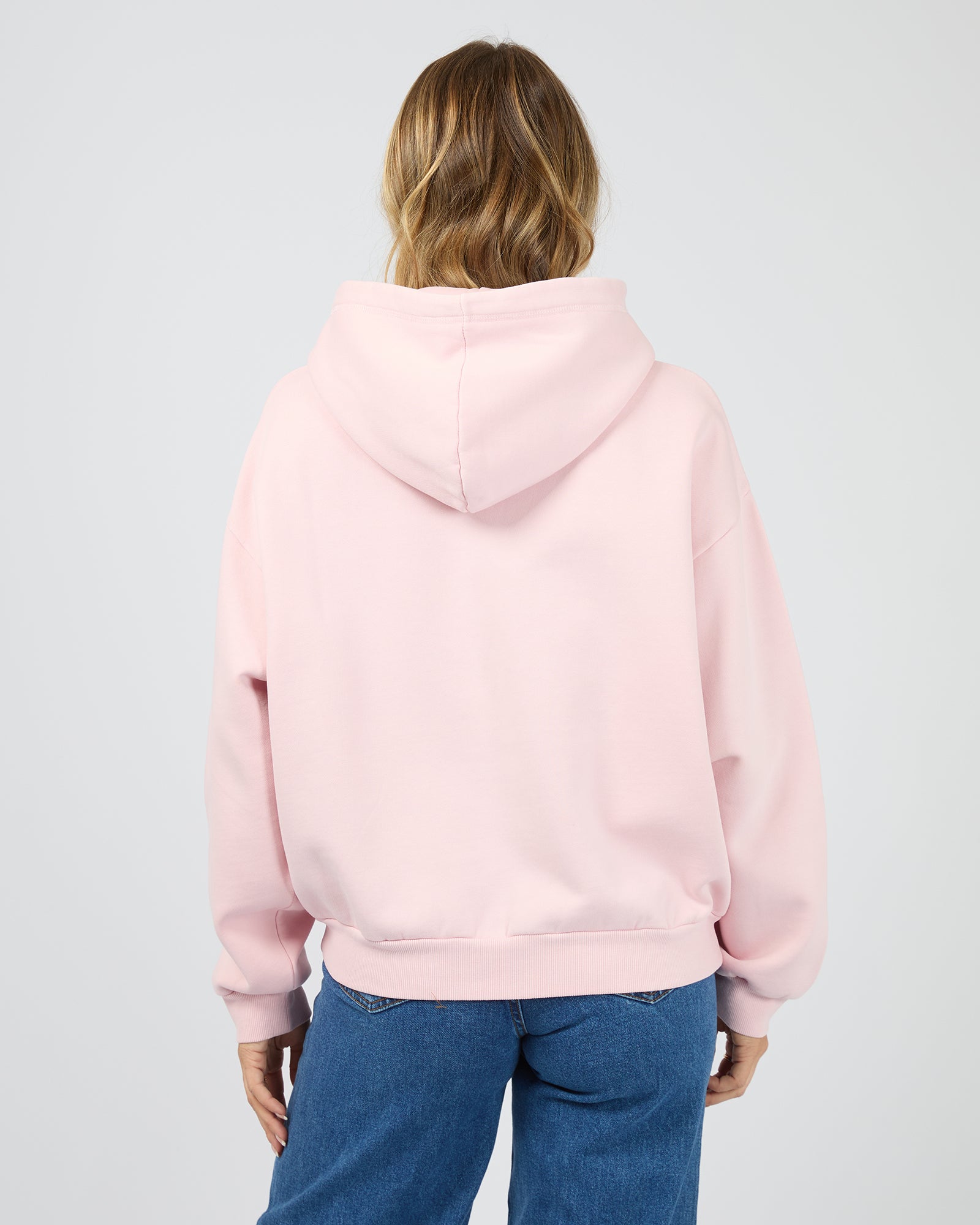 Person wearing a pink hoodie from behind on a light gray background