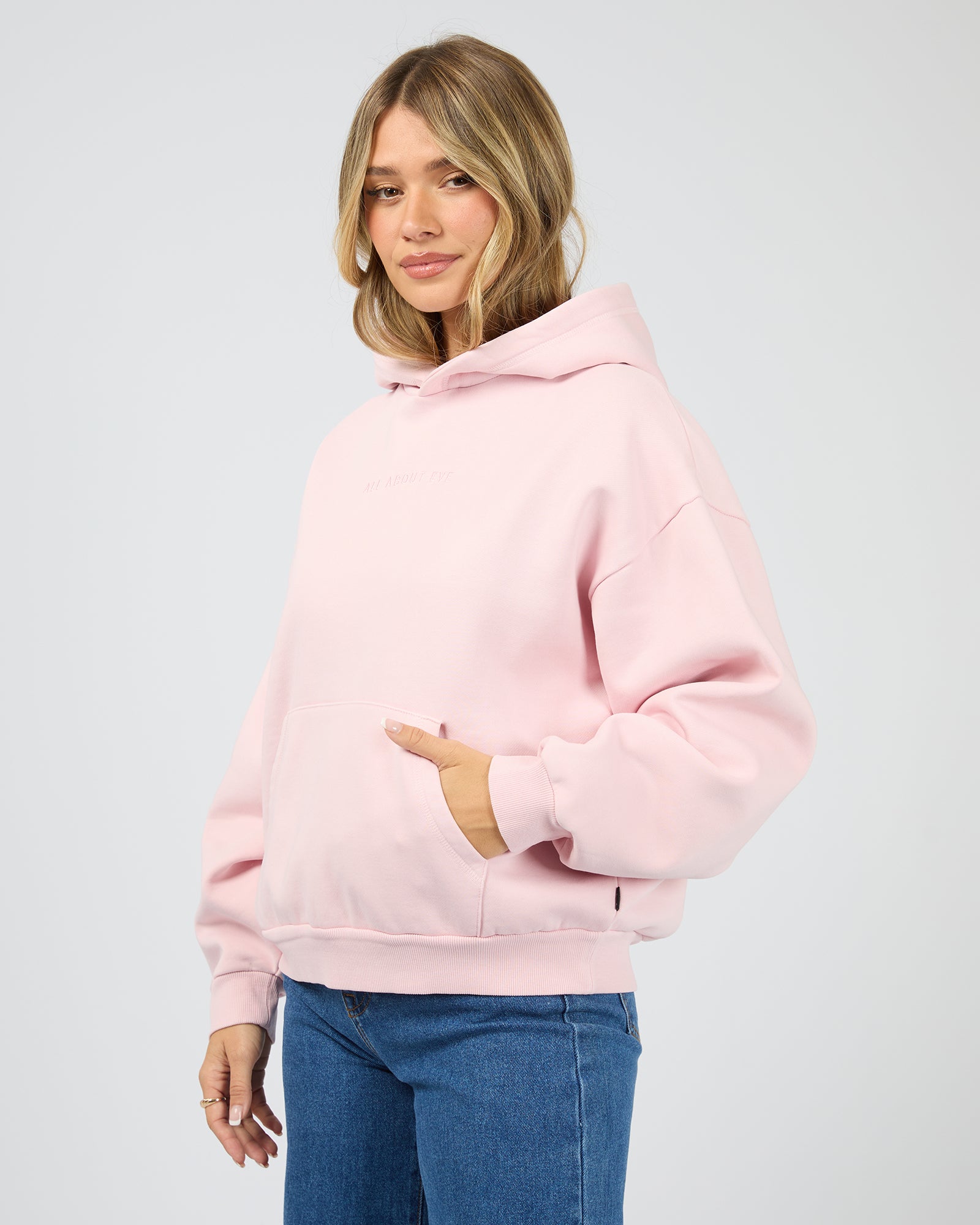 Woman wearing a pink hoodie on a light gray background