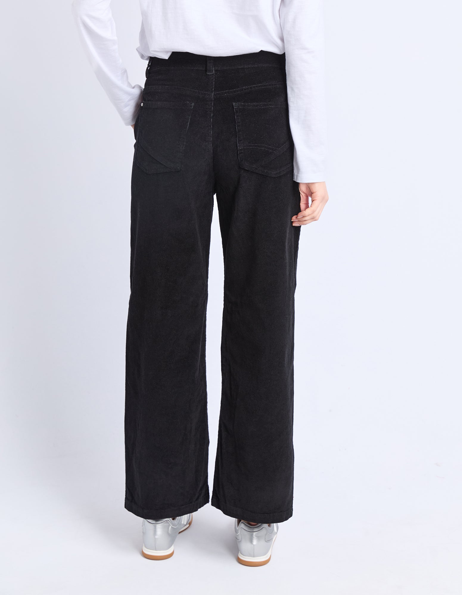 Person wearing black wide-leg jeans and a white shirt on a white background