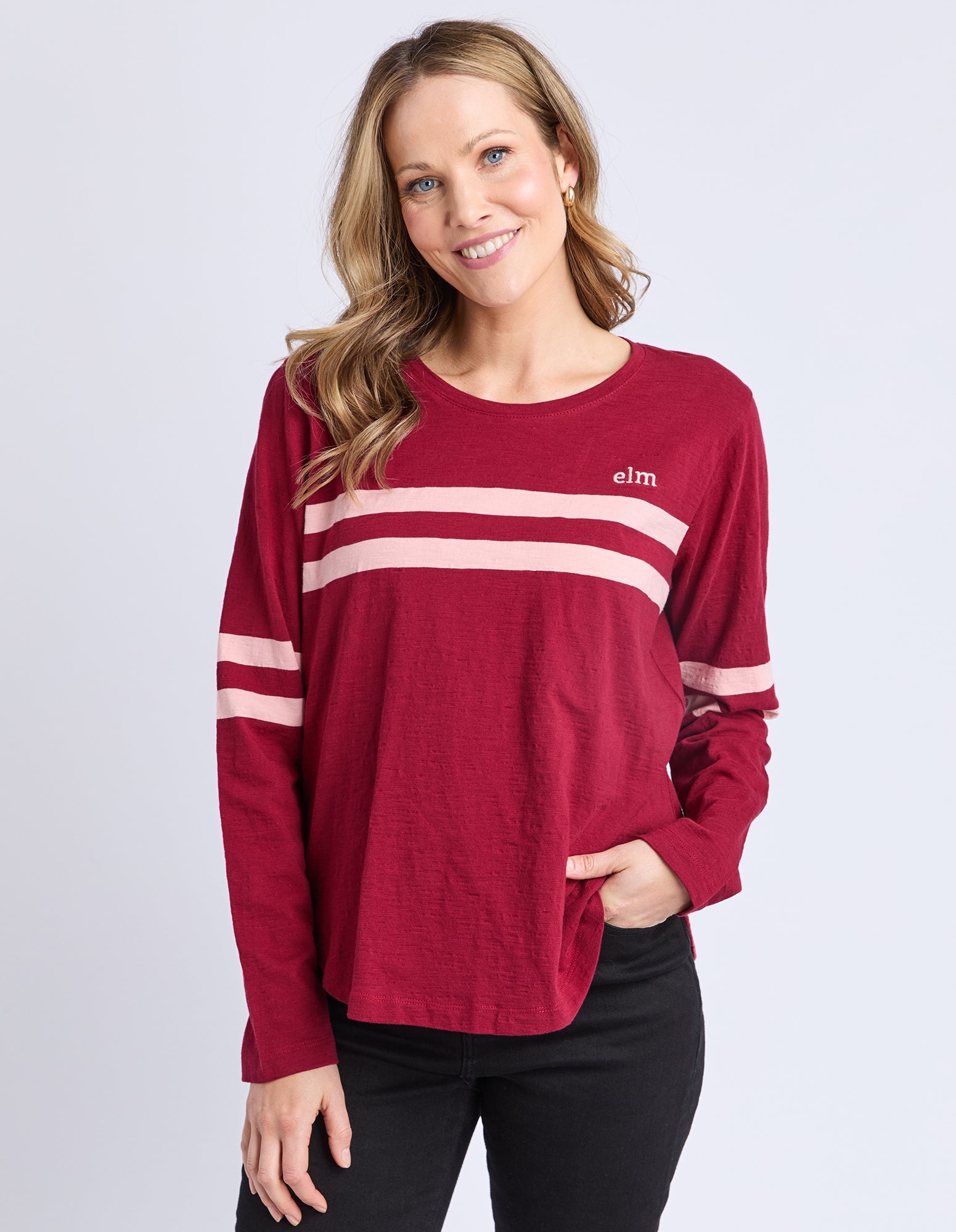 Woman wearing a red long-sleeve shirt with white stripes on a light gray background