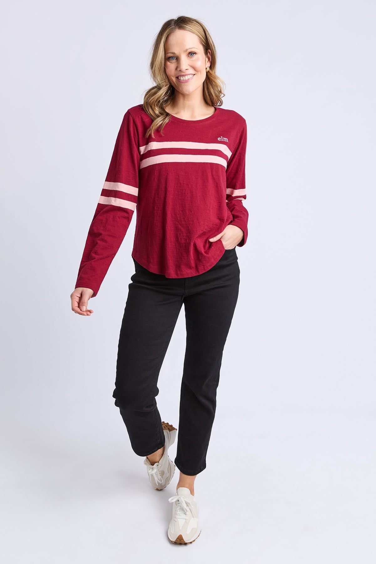 Woman wearing a red and white striped long-sleeve shirt with black pants on a light gray background