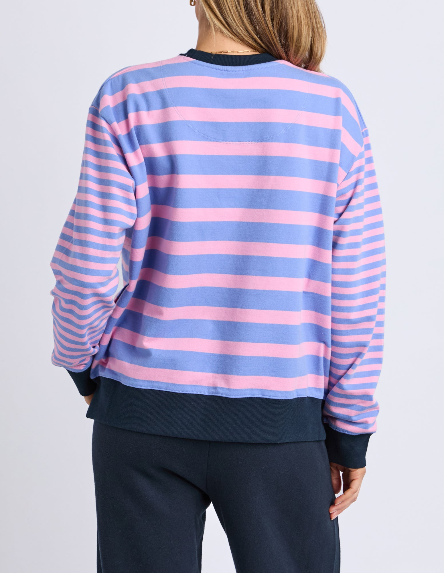 Person wearing a pink and blue striped sweater on a plain background