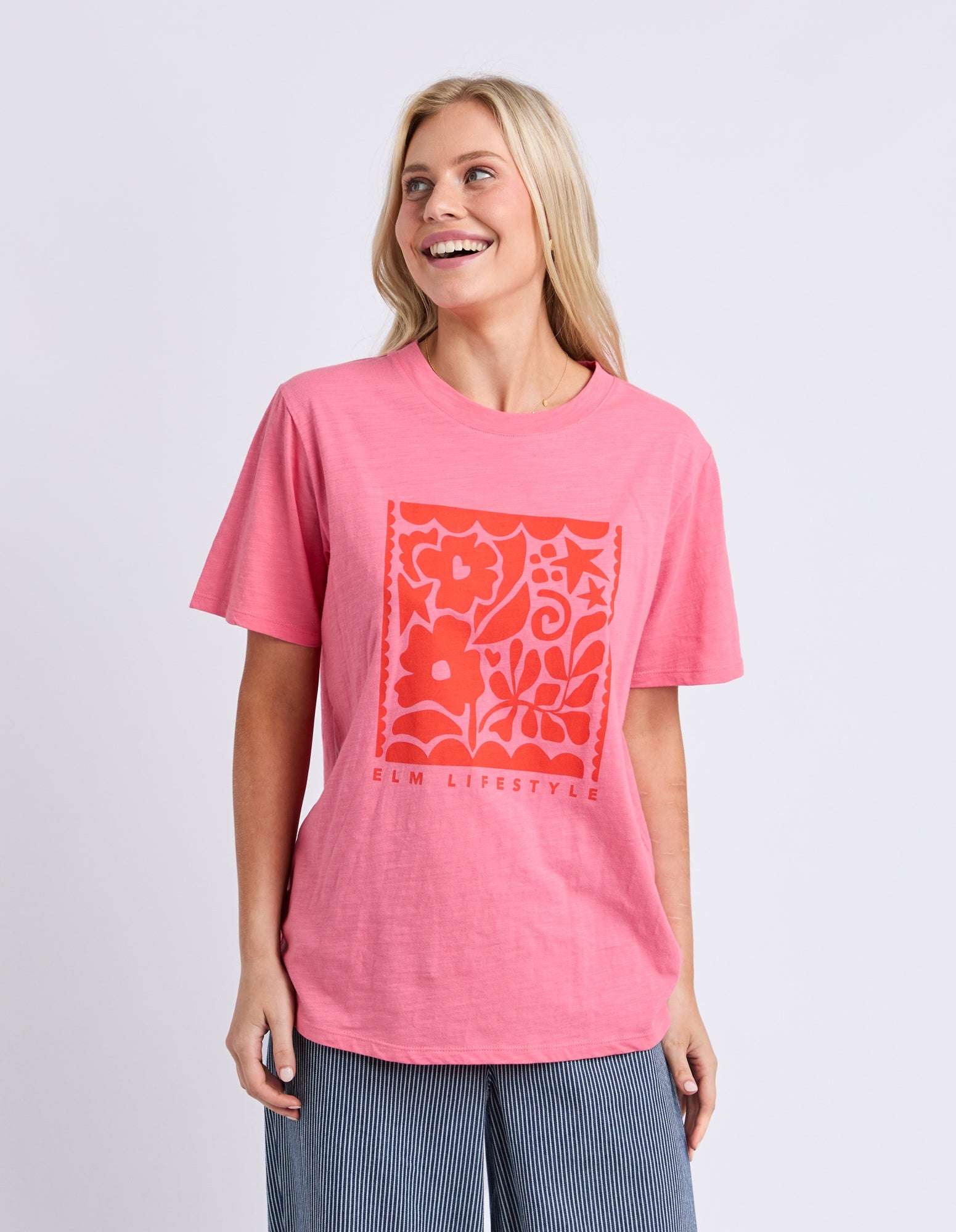 Woman wearing a pink t-shirt with a red floral design on a light gray background