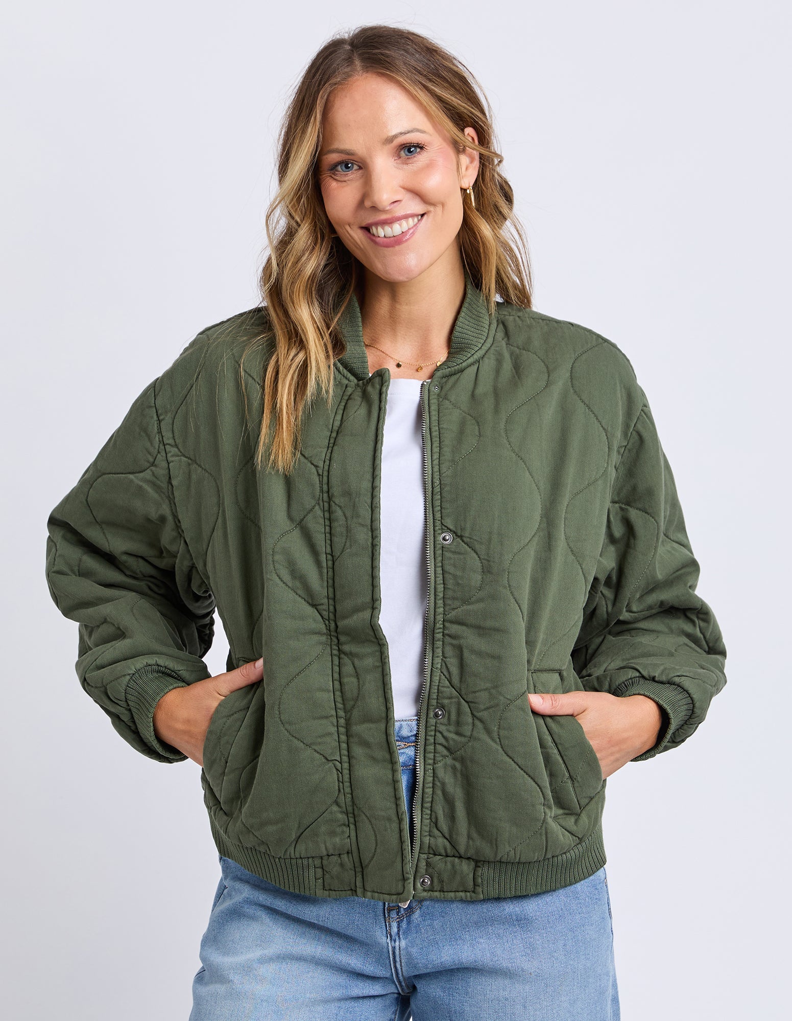 Woman wearing a green quilted jacket on a white background