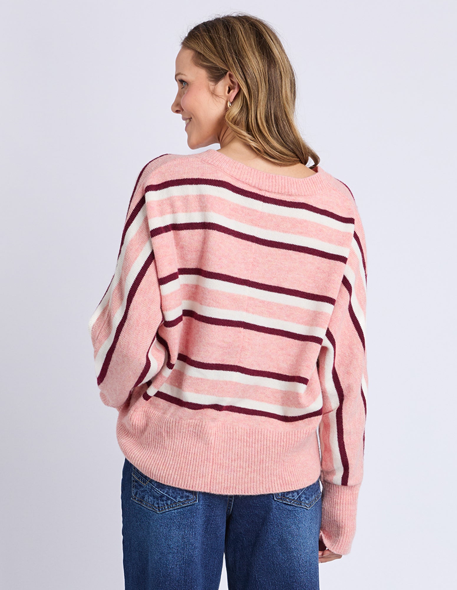 Woman wearing a pink and red striped sweater on a light gray background
