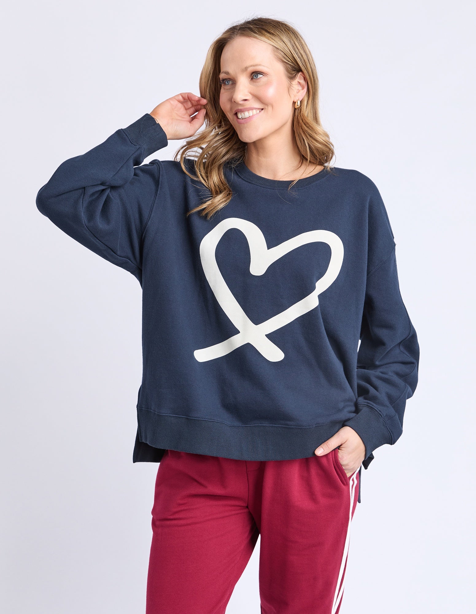 Woman wearing a navy sweatshirt with a white heart design on a light gray background