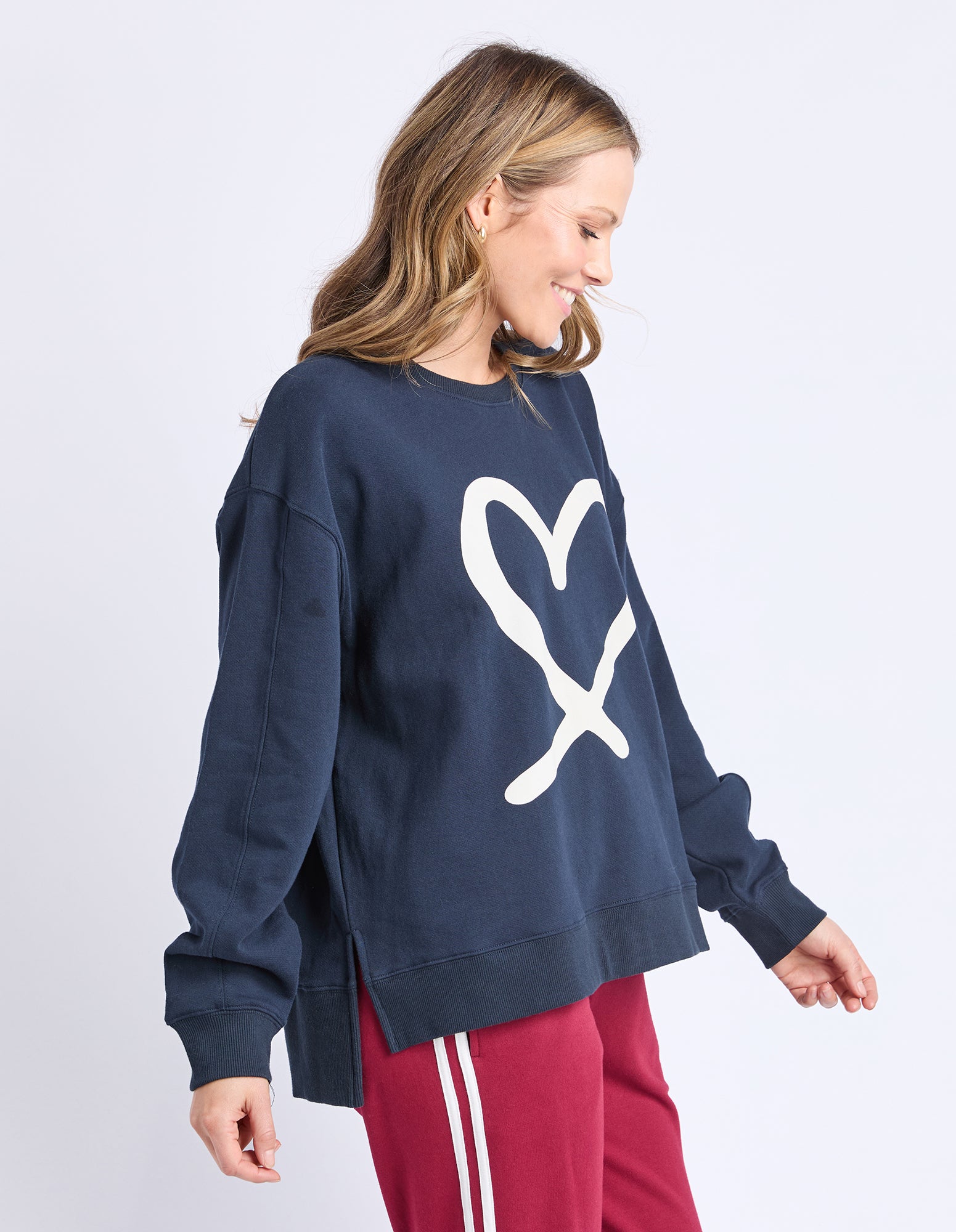 Woman wearing a navy sweatshirt with a white logo on a light gray background