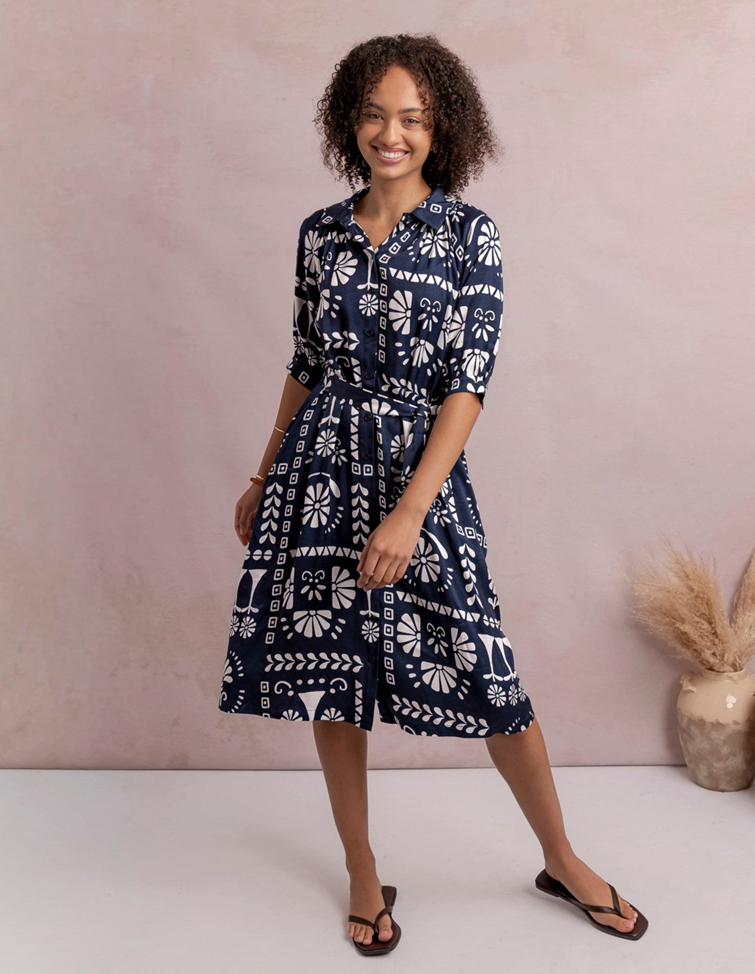 Woman wearing a navy blue dress with white patterns against a beige background