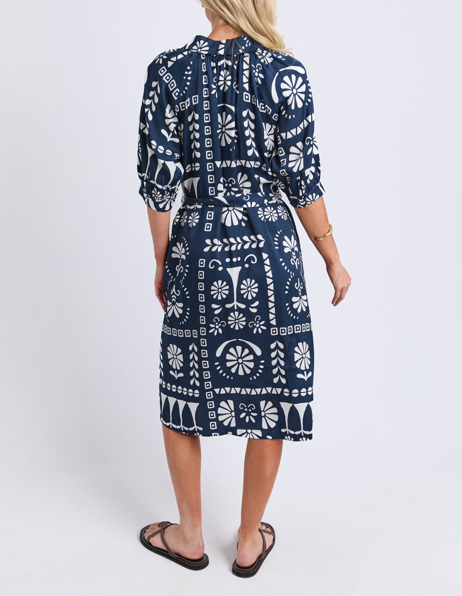 Woman wearing a navy blue dress with white patterns on a white background