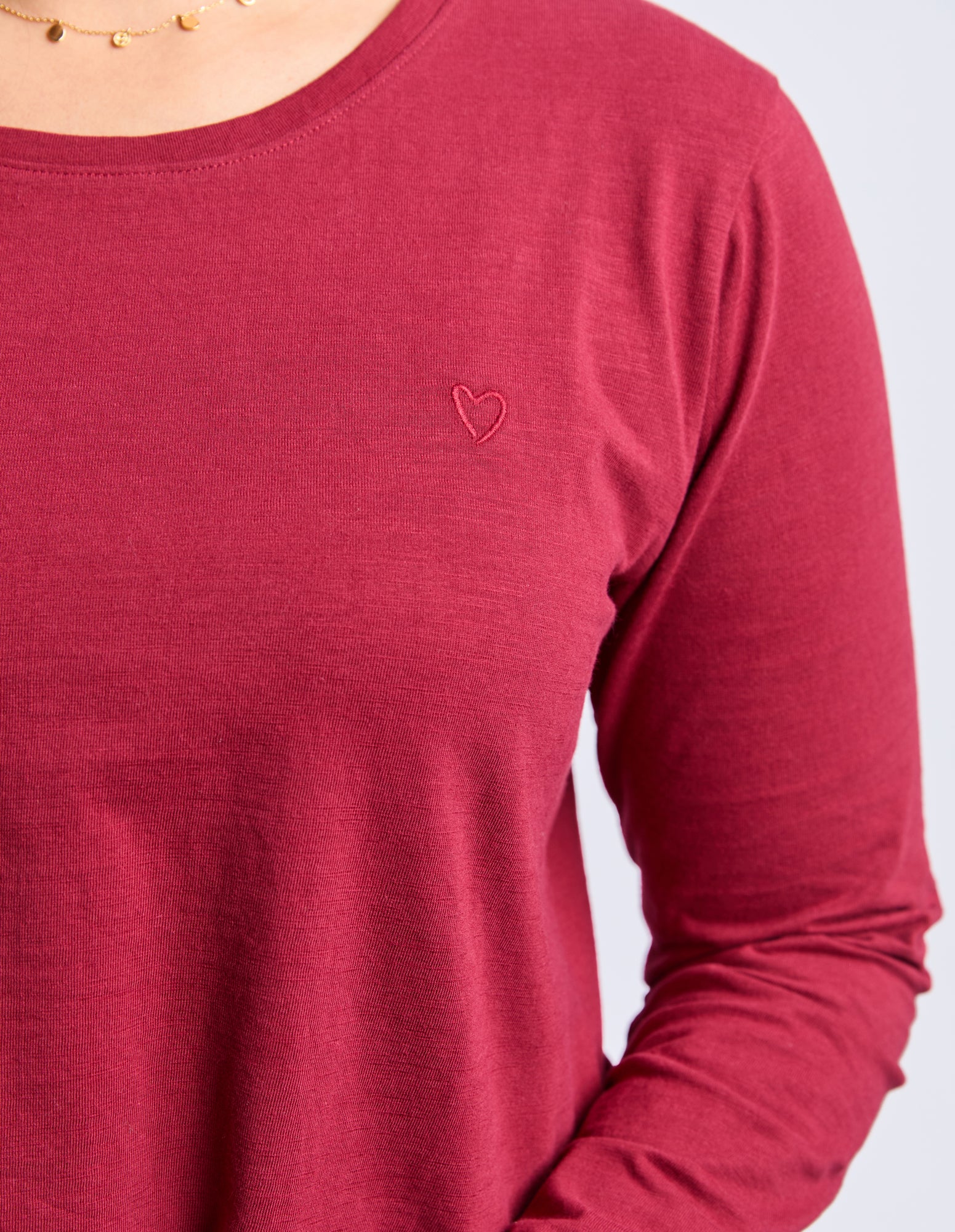 Red long-sleeve shirt with a heart emblem on a white background