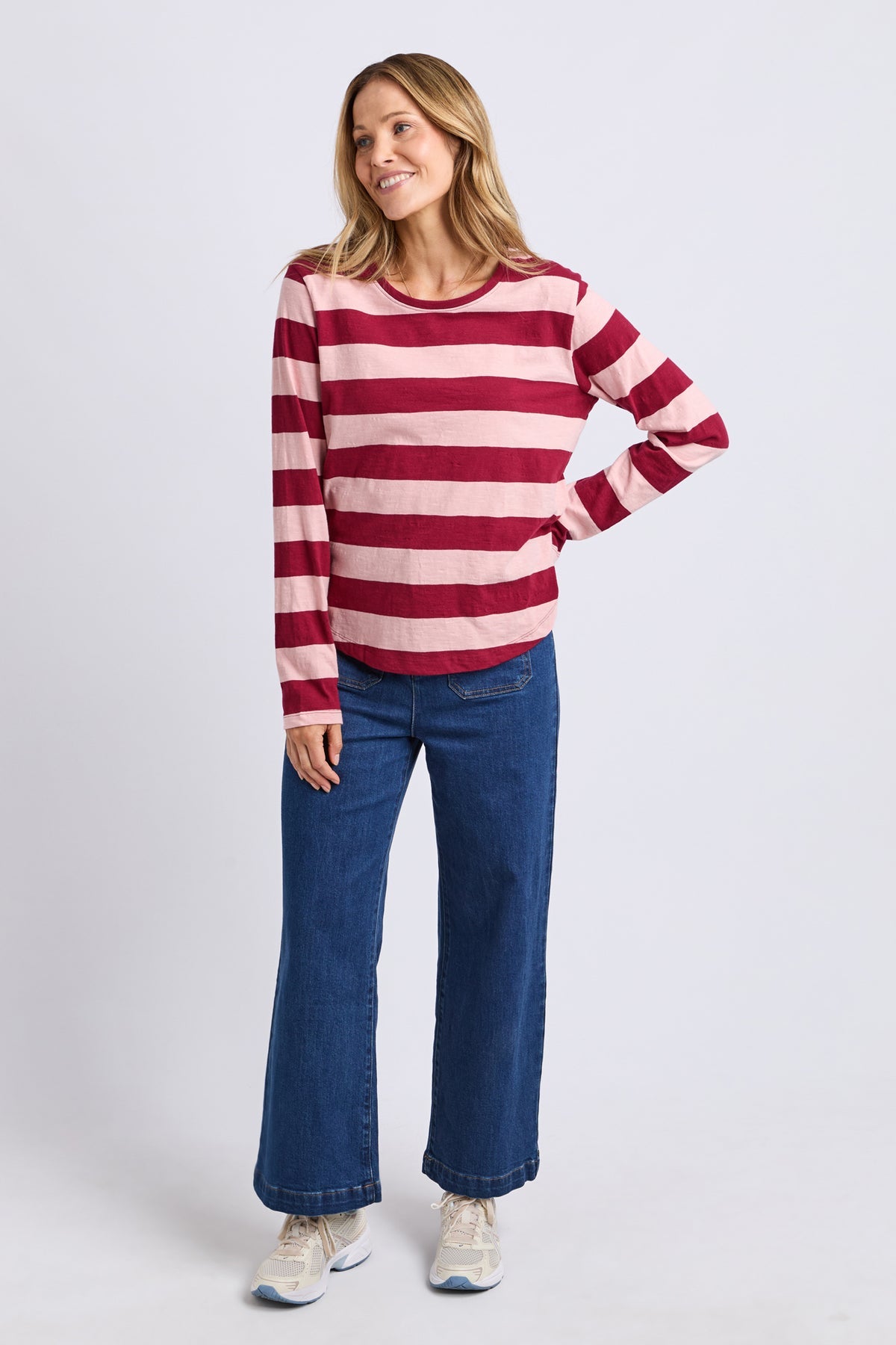 Woman wearing a red and white striped sweater and blue jeans on a white background