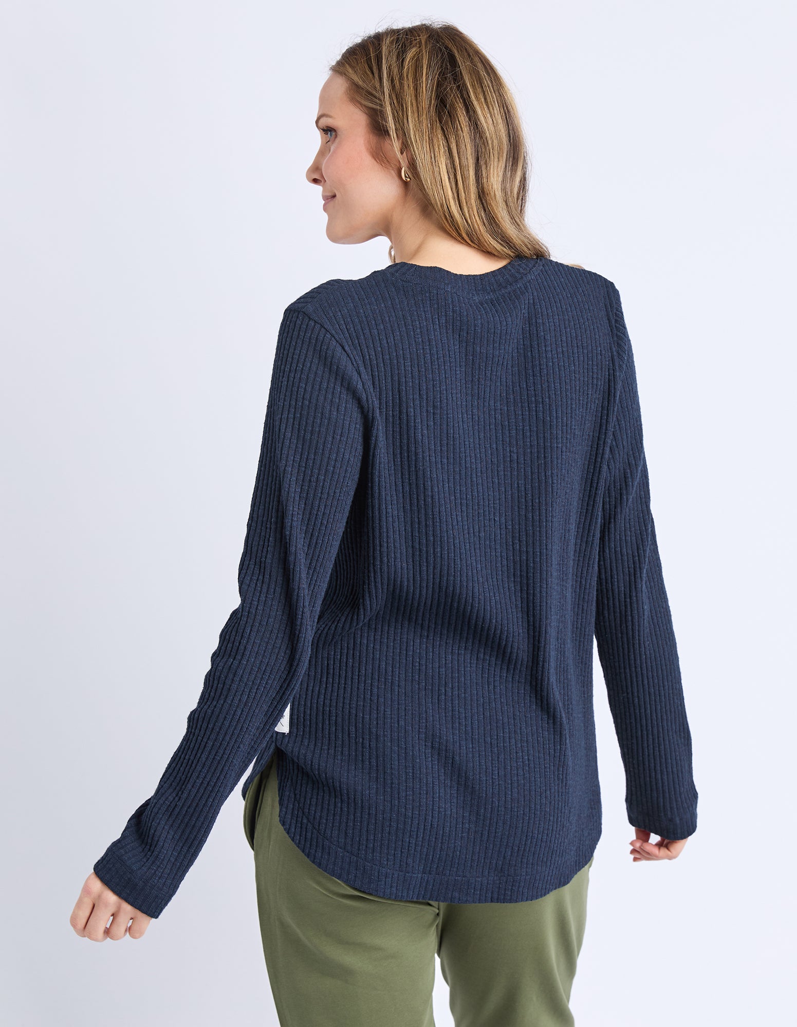 Woman wearing a blue sweater and green pants on a white background