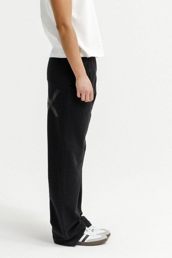 Person wearing black pants and white sneakers on a white background