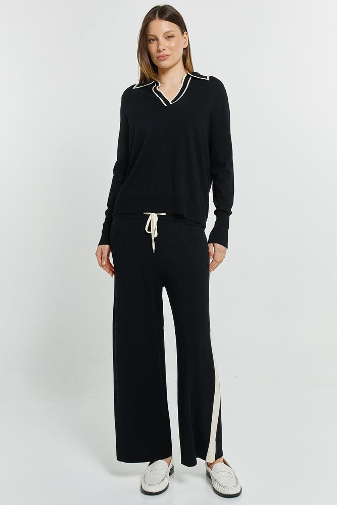 Woman wearing a black outfit with white accents on a white background