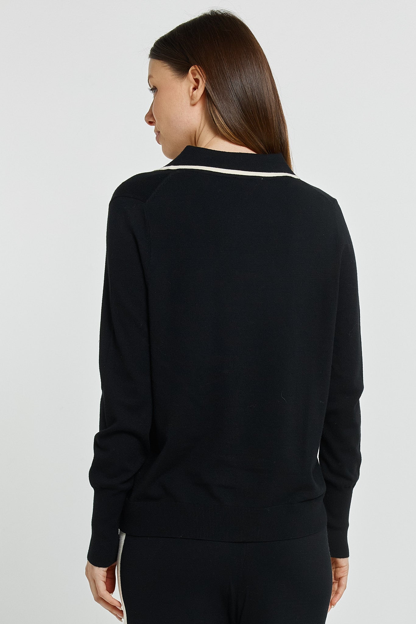 Woman wearing a black long-sleeve top with white trim on a light gray background