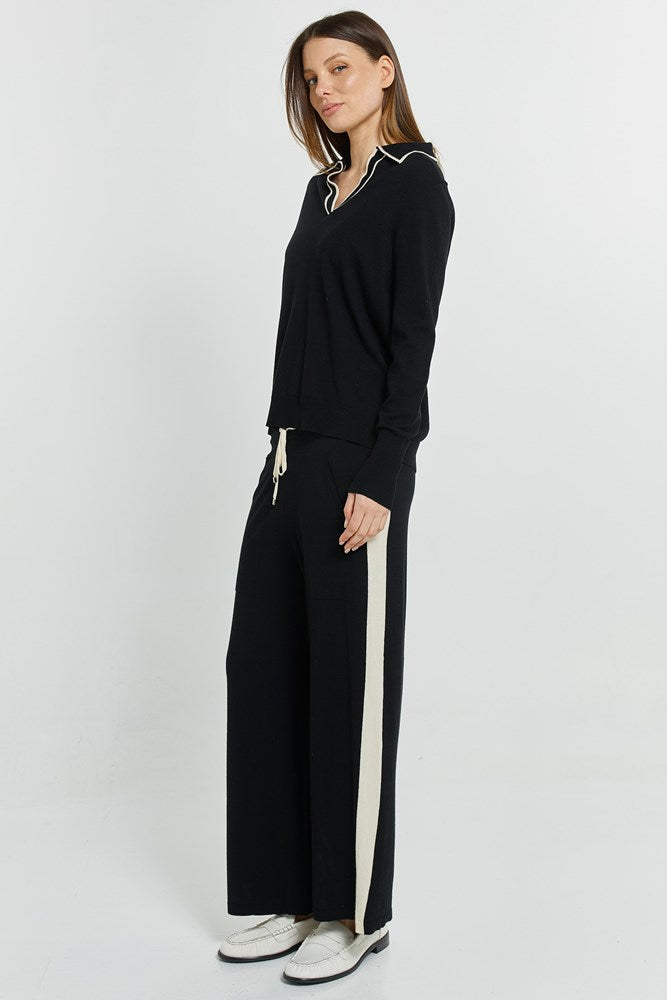 Woman wearing a black outfit with white accents on a white background