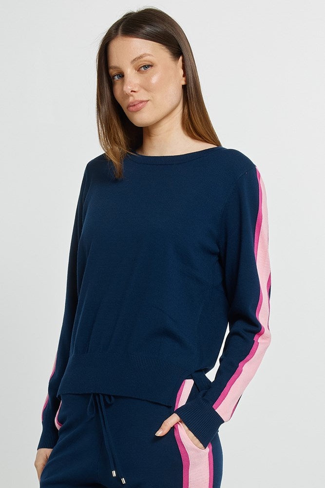 Woman wearing a navy blue outfit with pink accents on a plain background