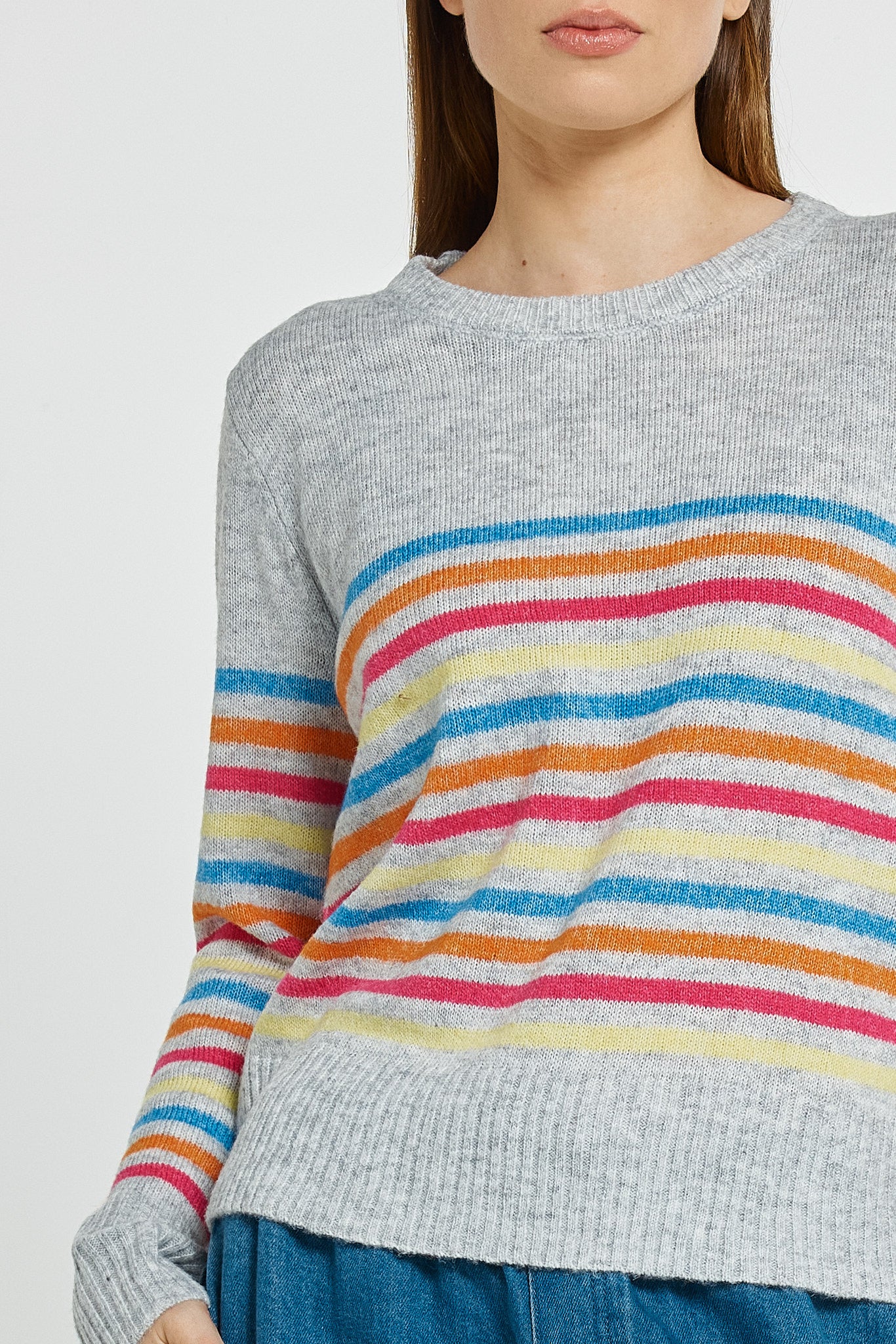 Gray sweater with colorful horizontal stripes worn by a person on a light gray background