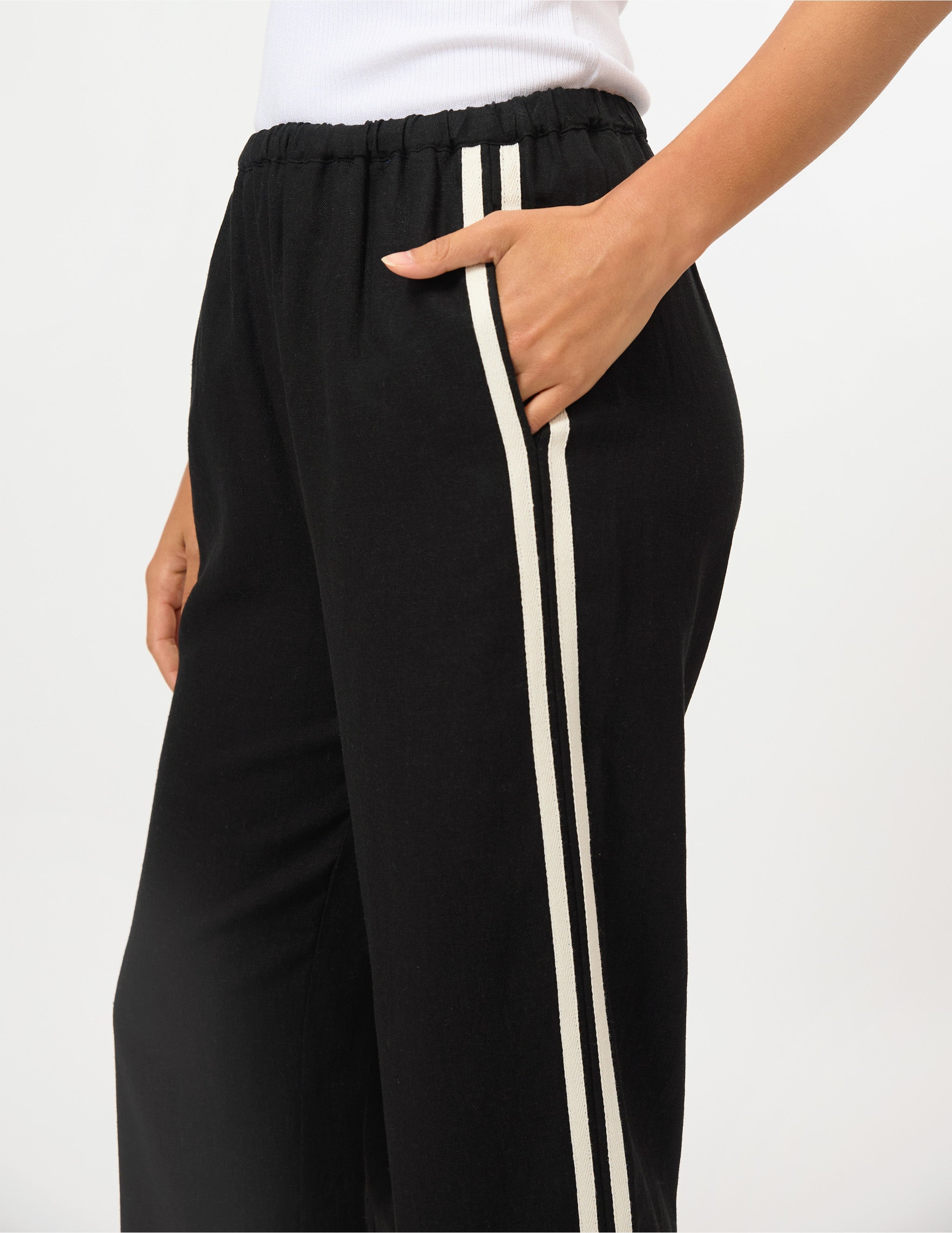 Black wide-leg sweatpants with double cream stripes down the side, shown on a model against a plain white background.