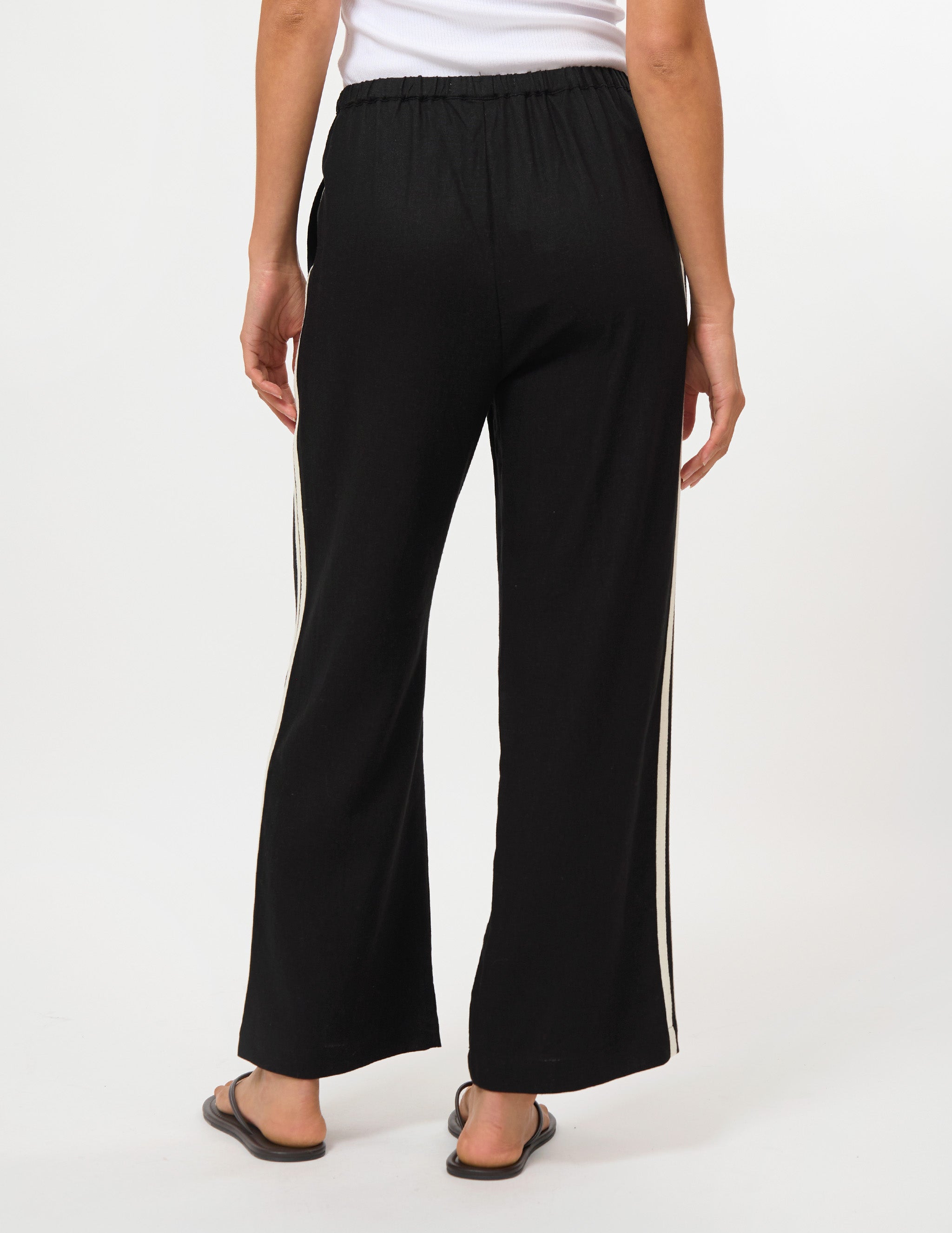 Black wide-leg cropped pants with white side stripes, shown on a model from the back against a white studio background.