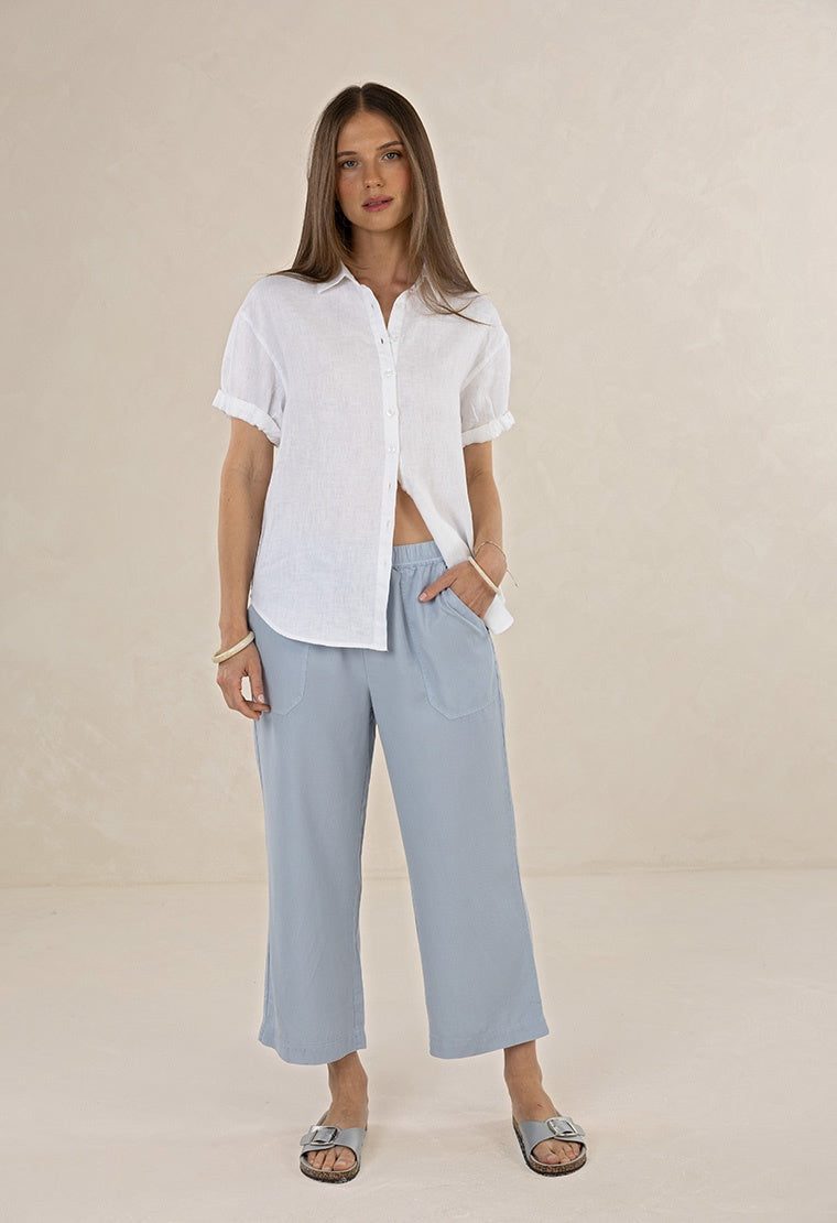 Woman wearing a white shirt and light blue pants on a beige background