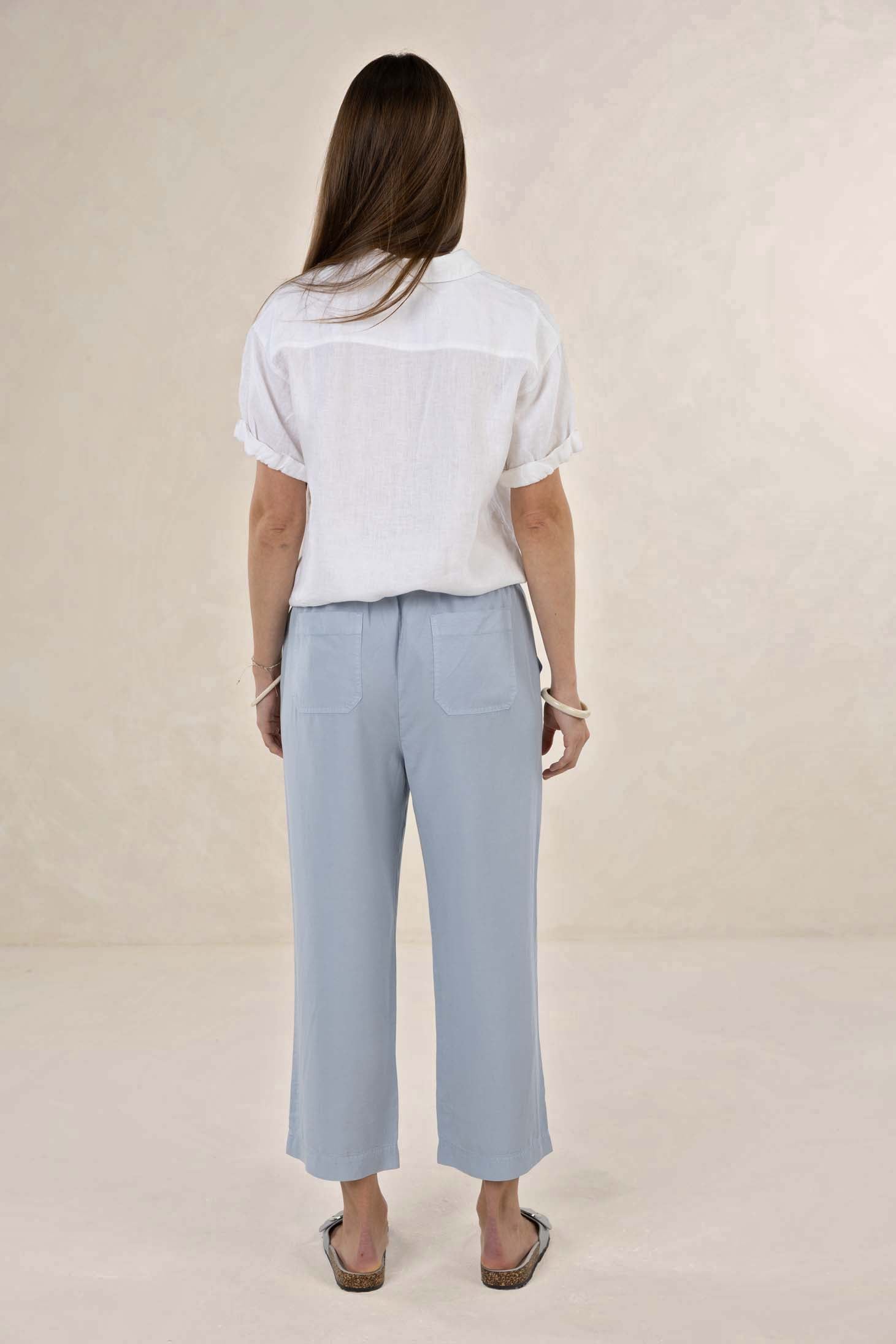 Person wearing a white shirt and light blue pants on a beige background