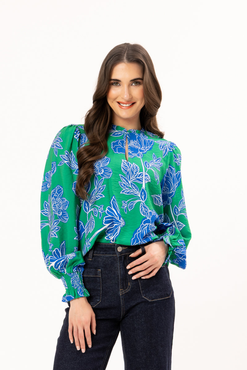Woman wearing a green floral blouse with blue flowers on a white background