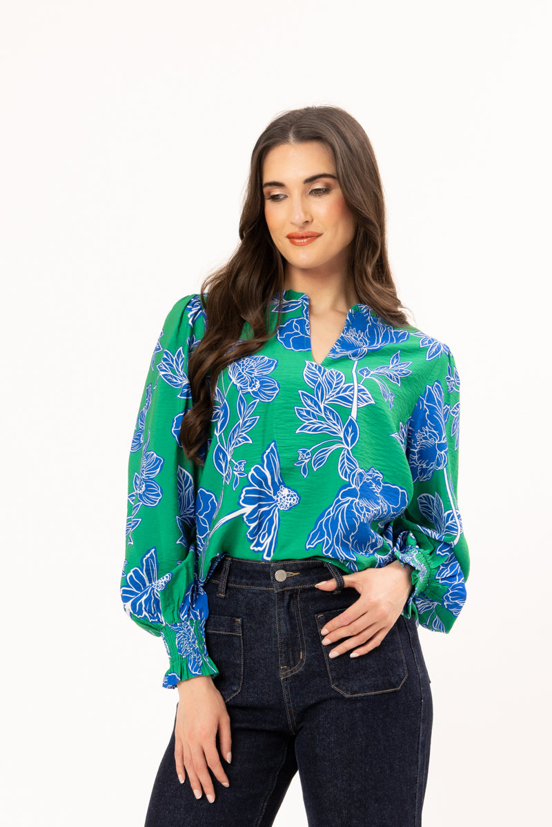Woman wearing a green floral blouse with blue flowers on a white background