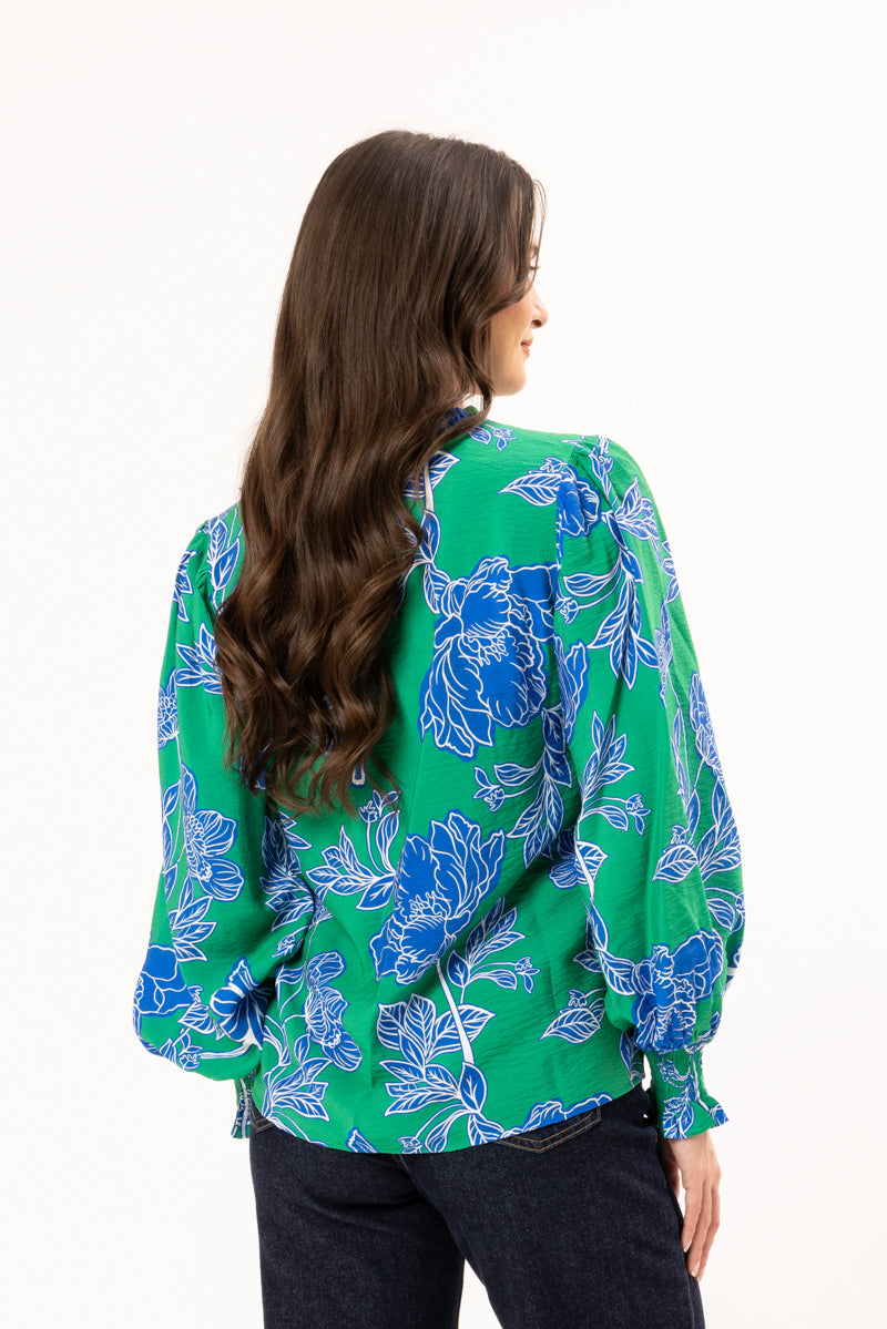 Woman wearing a green floral blouse on a white background