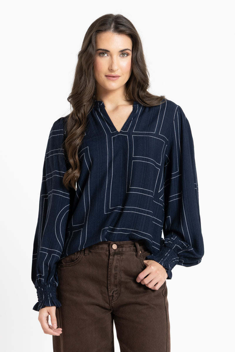 Woman wearing a dark blue blouse with white patterns on a white background